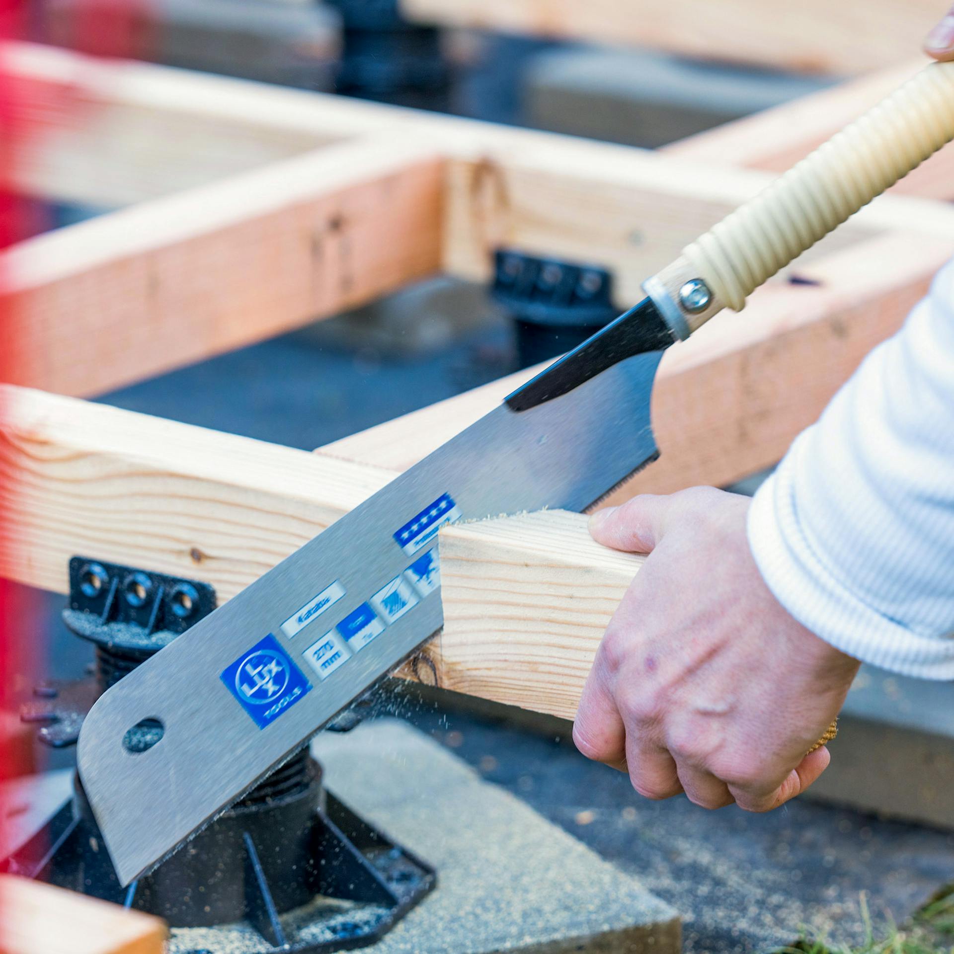 Ein Holzbalken wird mit einer Japansäge abgesägt