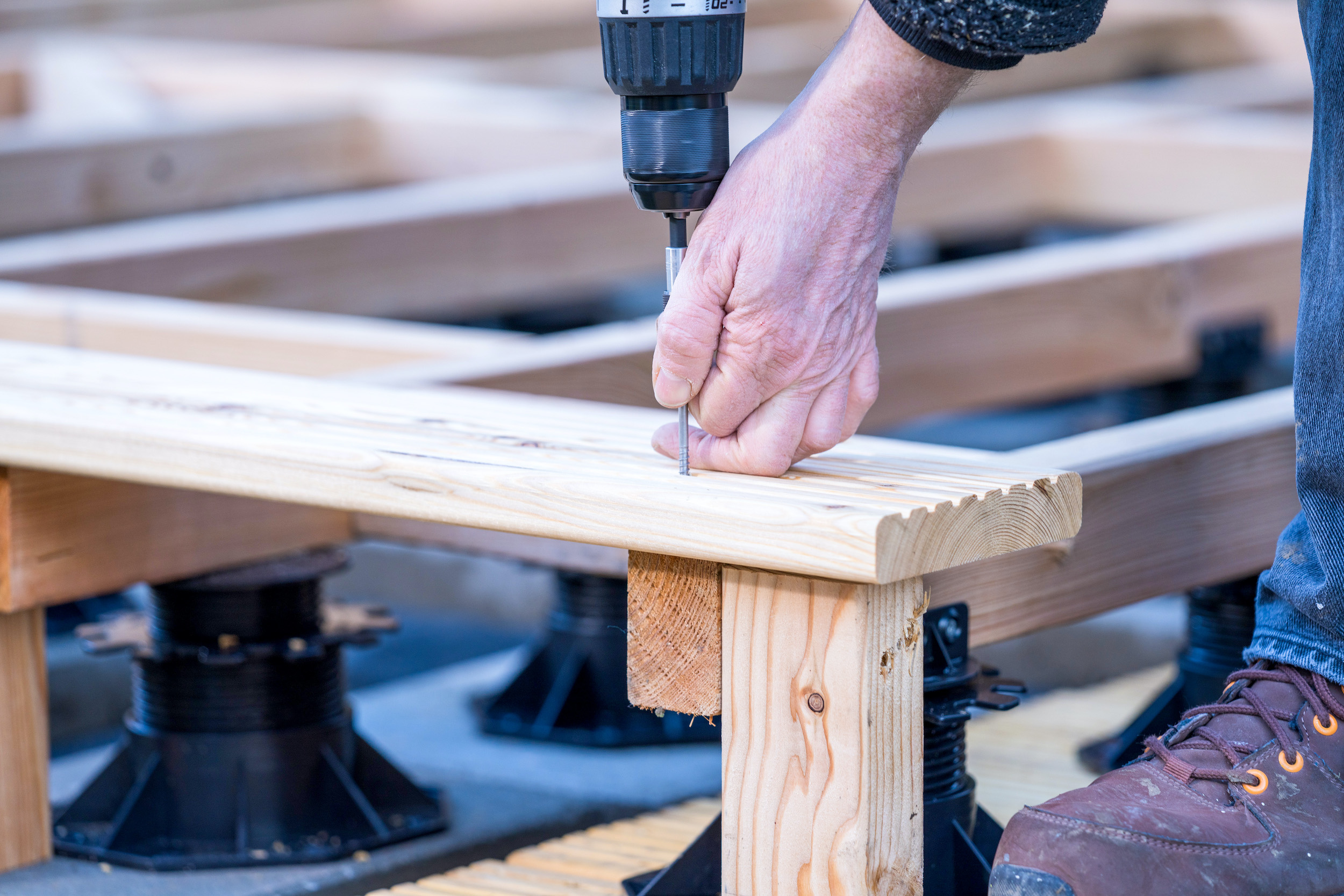 Una mano avvita un’asse per terrazza a una sottostruttura