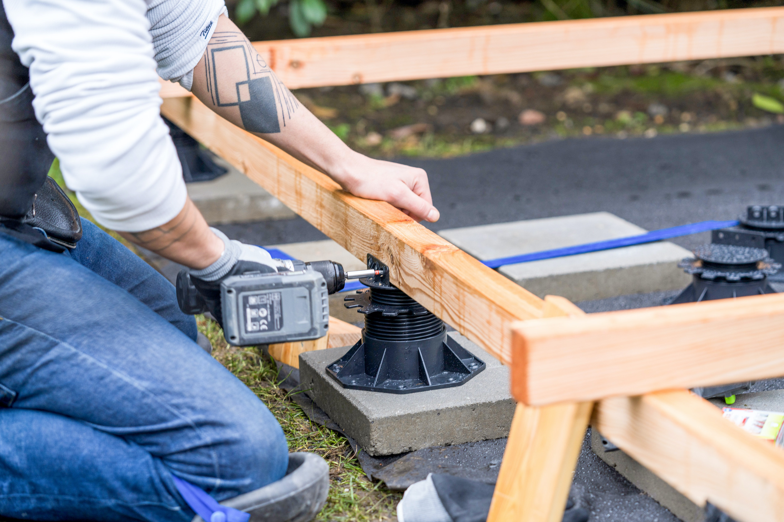 Ein Stellfuß wird mit einem Holzbalken verschraubt.