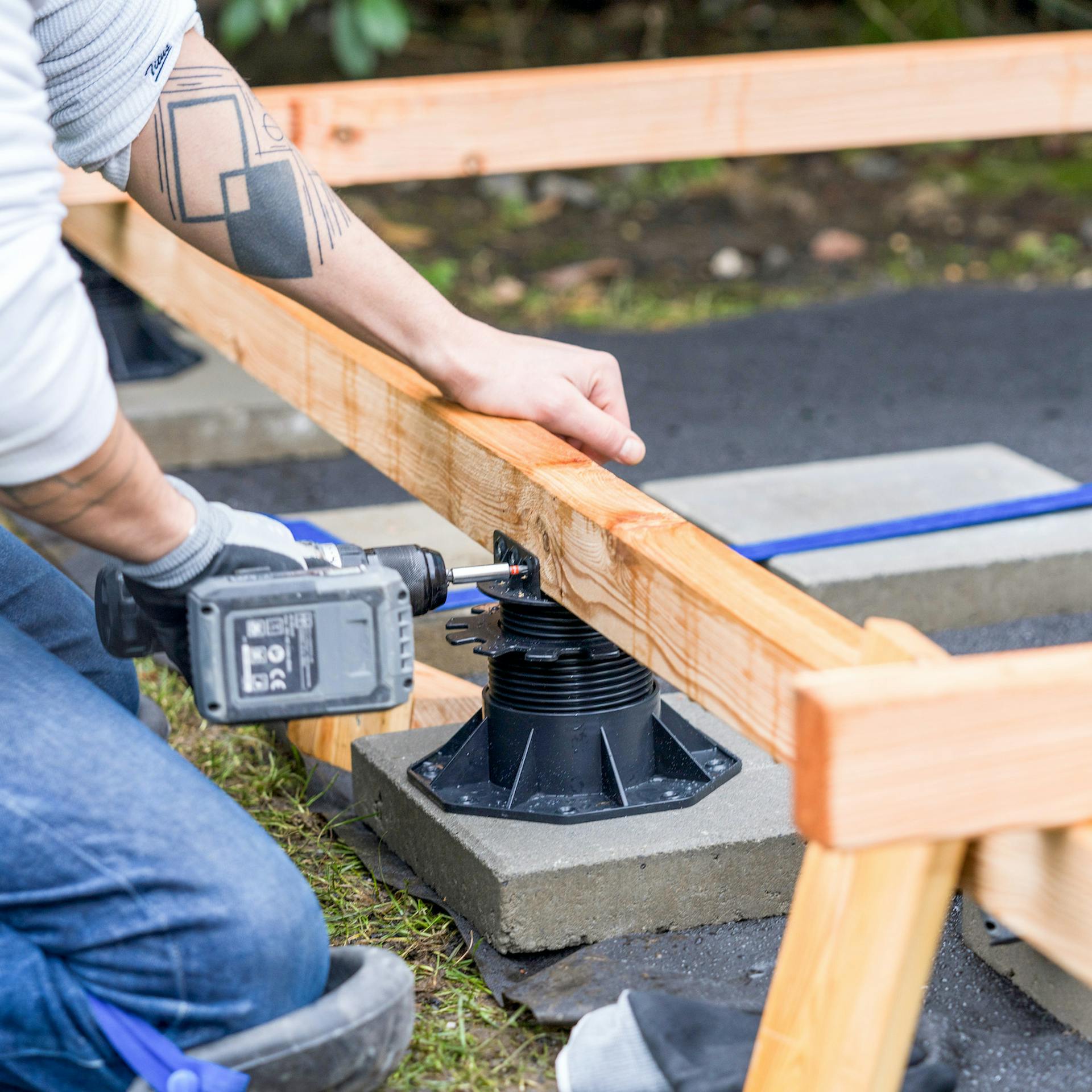 Ein Stellfuß wird mit einem Holzbalken verschraubt.