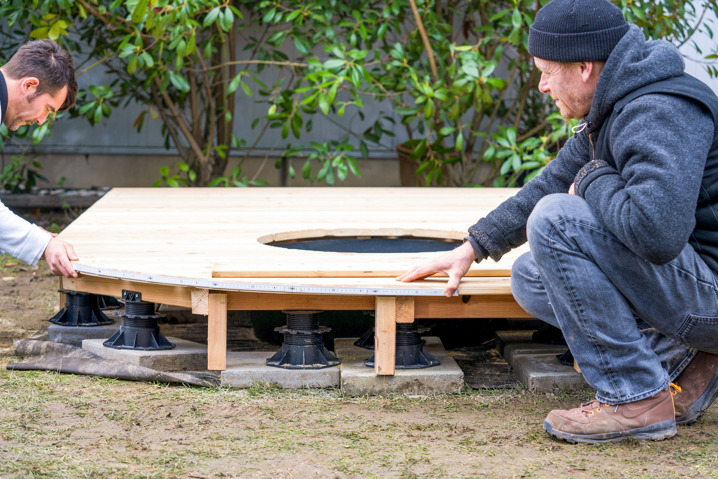 Amanti del fai-da-te misurano la curvatura di una terrazza in legno su supporti a palafitta