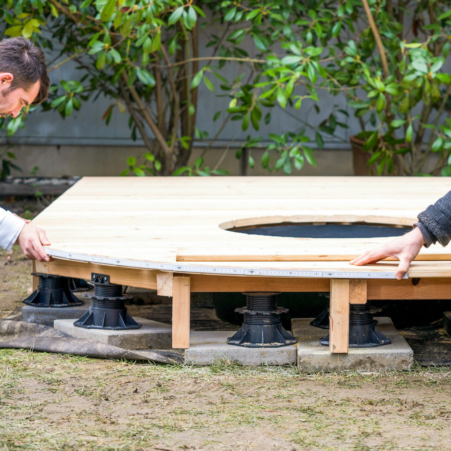 Zwei Männer halten einen Zollstock an eine Terrassenrundung.