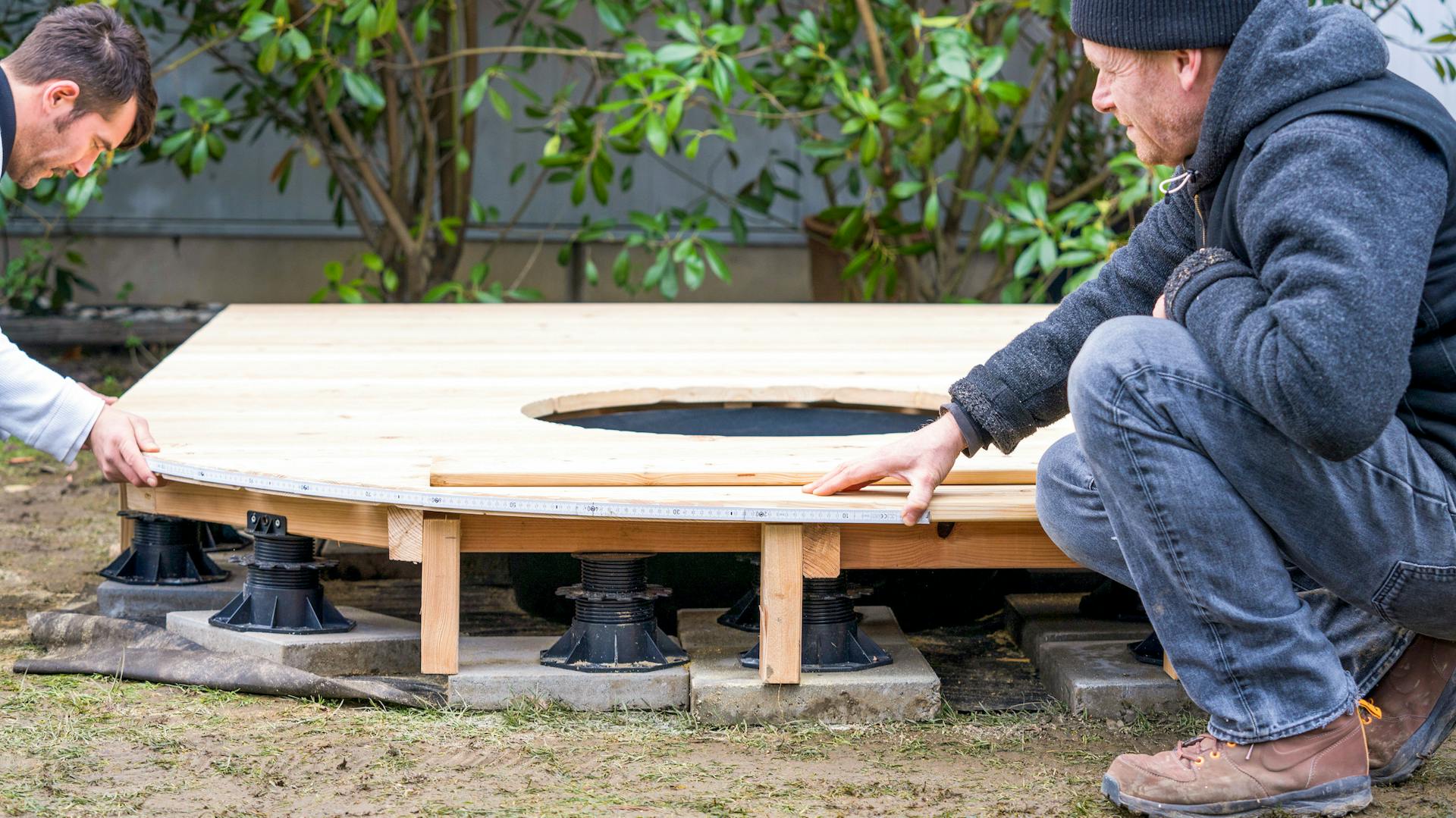 Amanti del fai-da-te misurano la curvatura di una terrazza in legno su supporti a palafitta