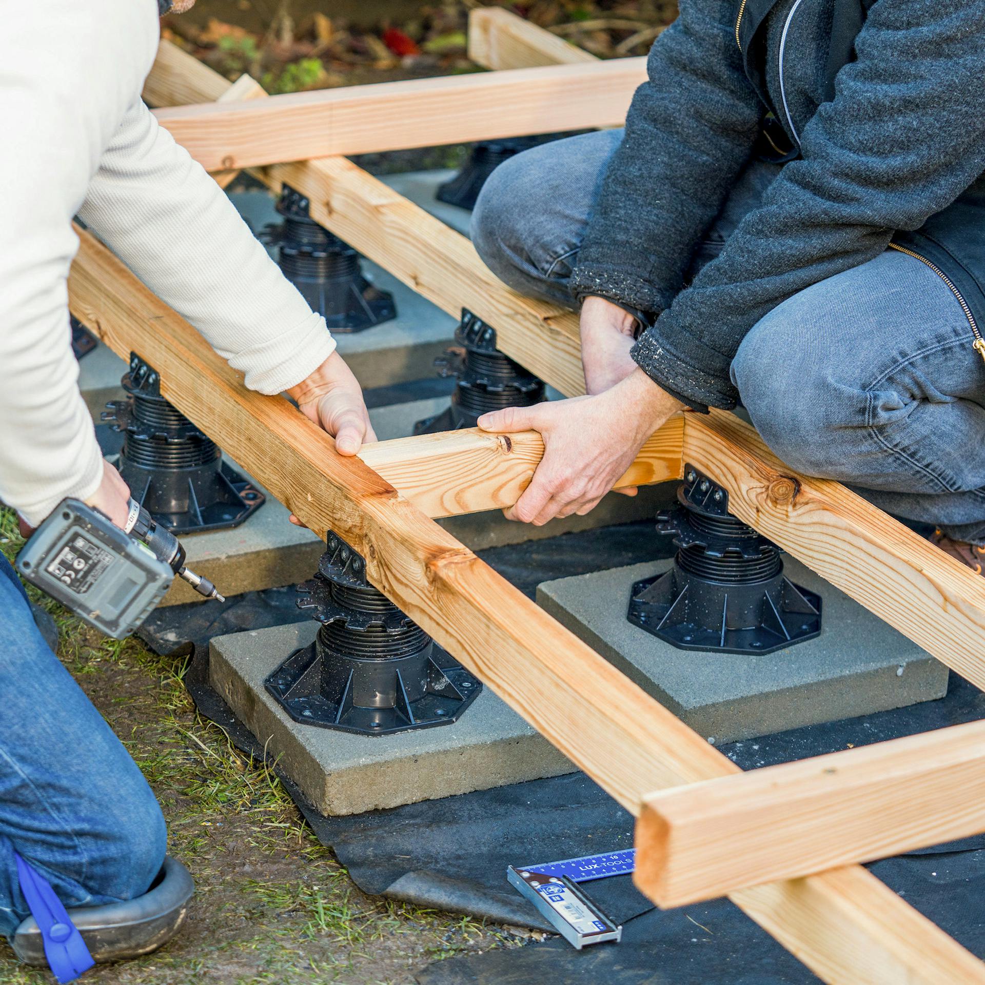 Zwei Männer schrauben Verbindungsbalken zwischen zwei Holzbalken