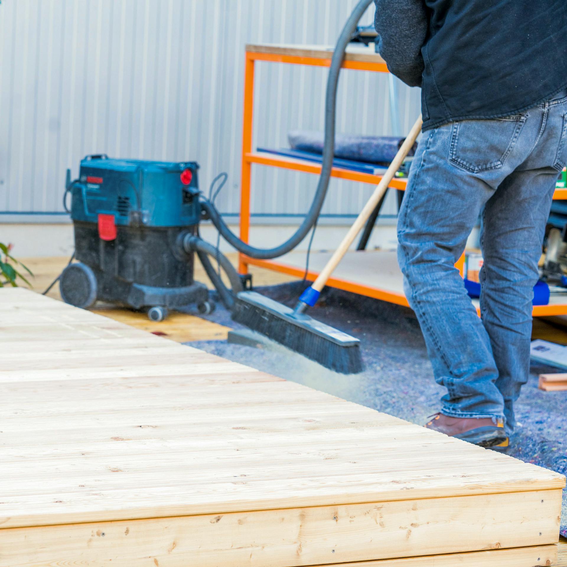 Ein Mann fegt eine Terrasse ab.