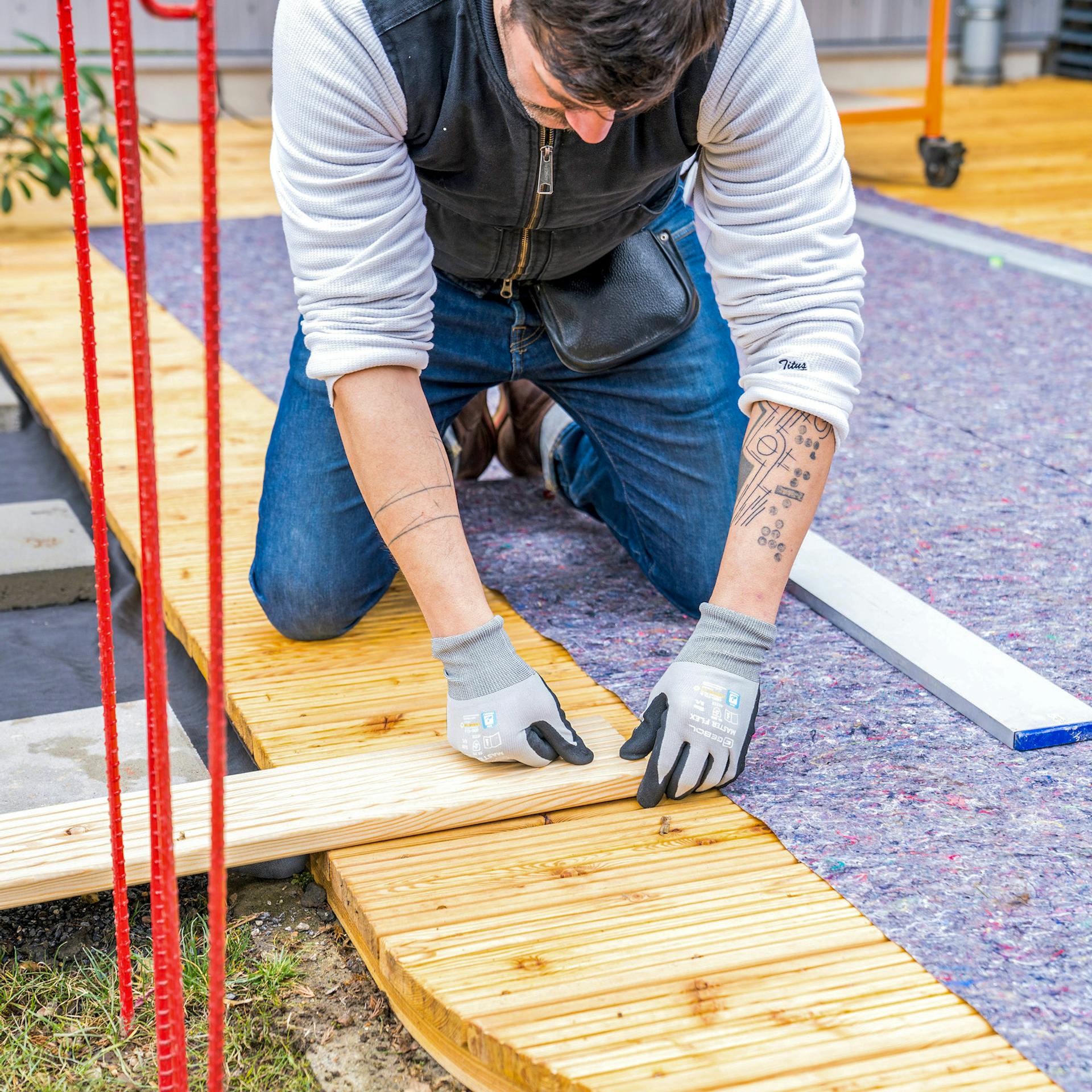 Ein Mann hält eine Terrassendiele auf eine Terrasse.