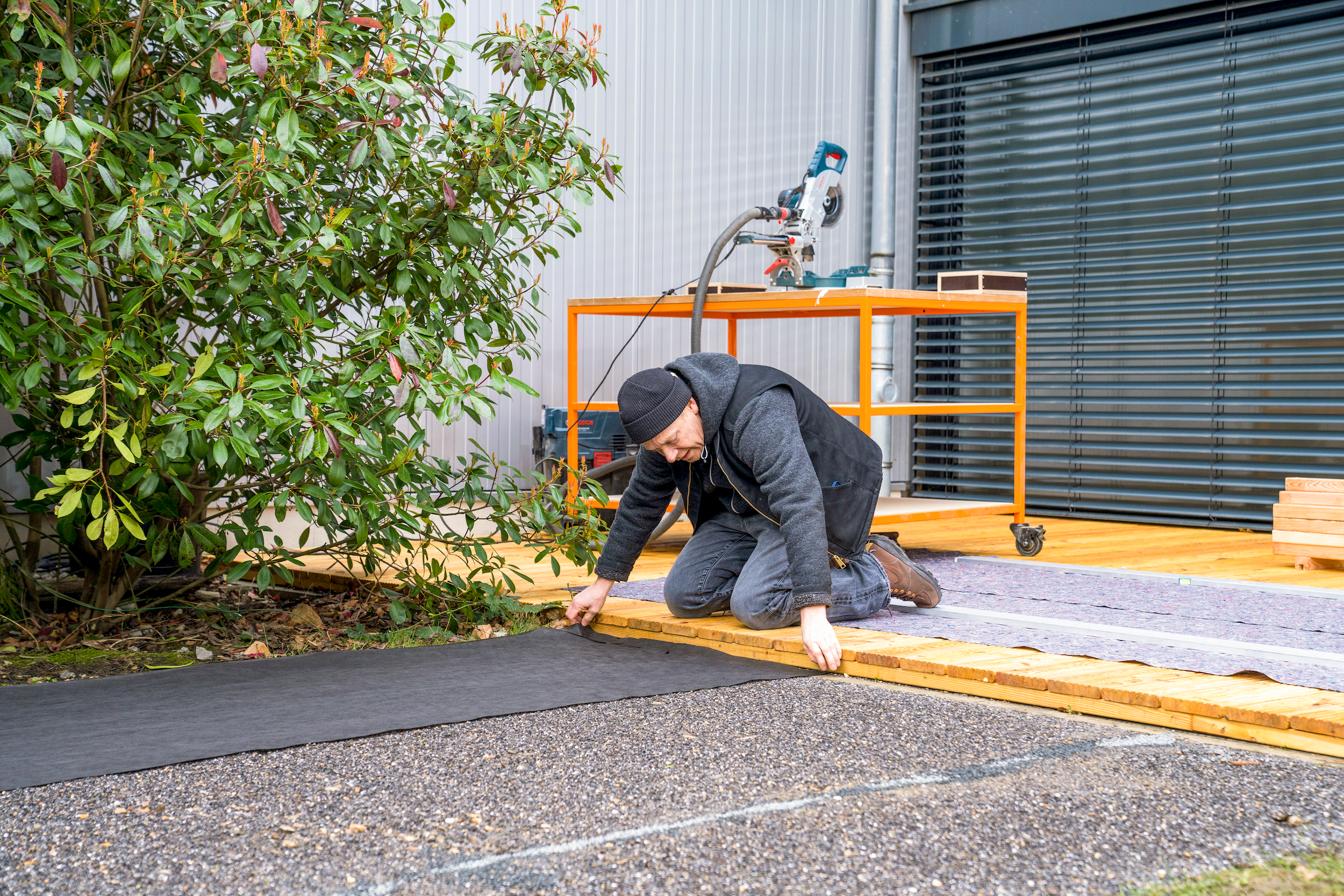 Un uomo tiene un telo anti erbacce su una terrazza.