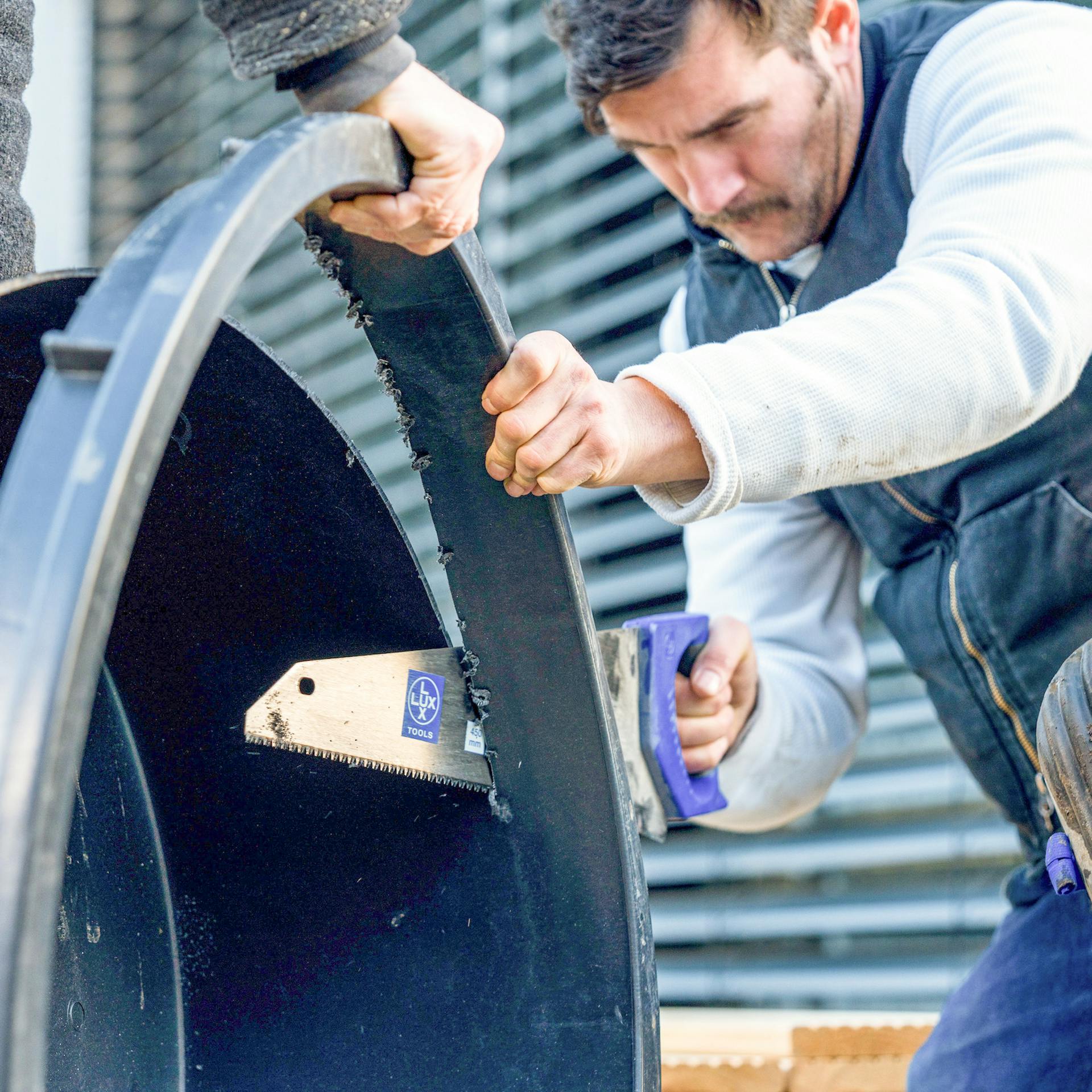Ein Mann sägt den Rand einer Plastikwanne ab.