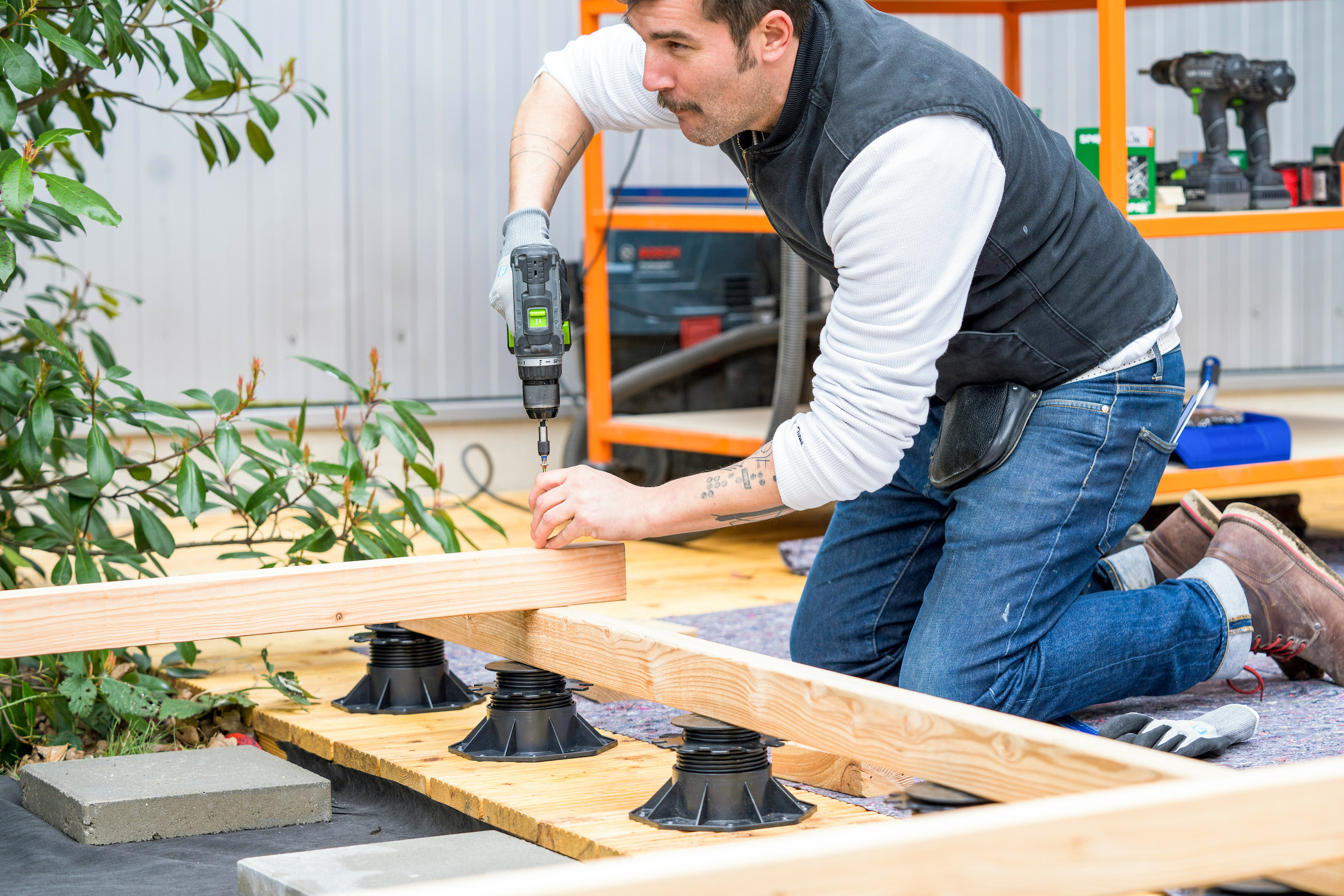 Un uomo avvita una trave di legno su una sottostruttura per terrazza.