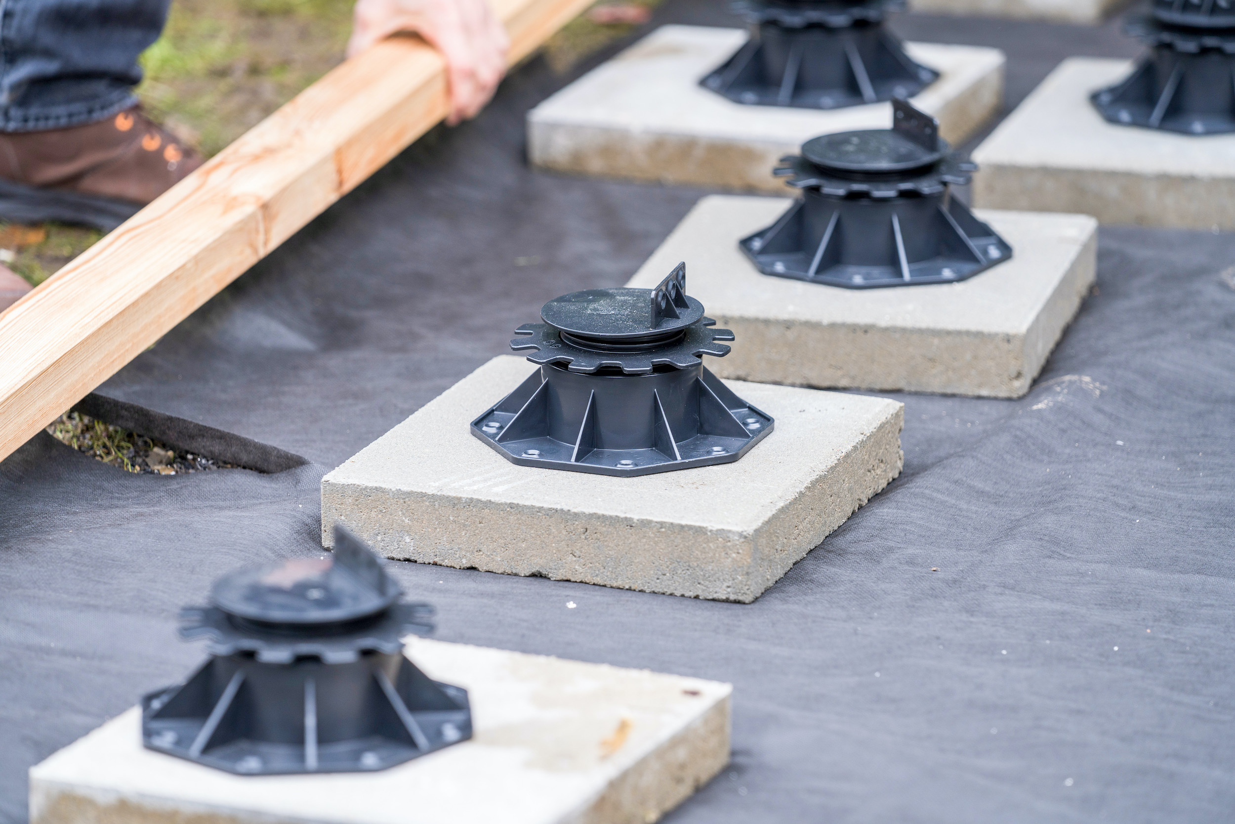 Diversi piedini di appoggio su lastre di calcestruzzo su un tessuto non tessuto di erbacce.