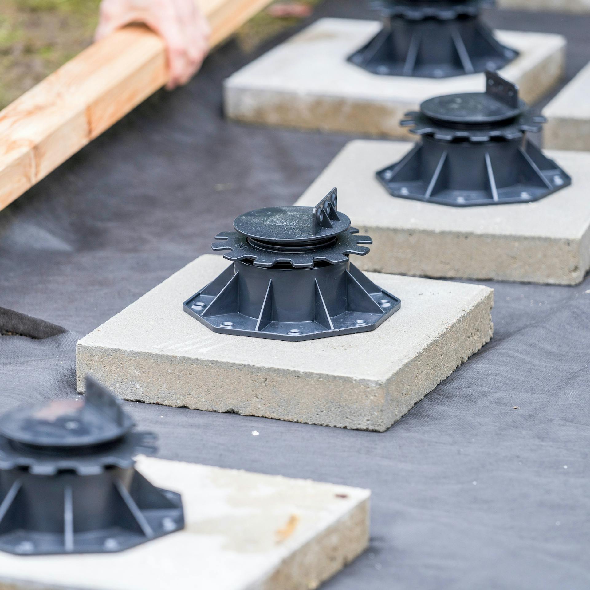 Mehrere Stellfüße auf Betonplatten auf einem Unkrautvlies.