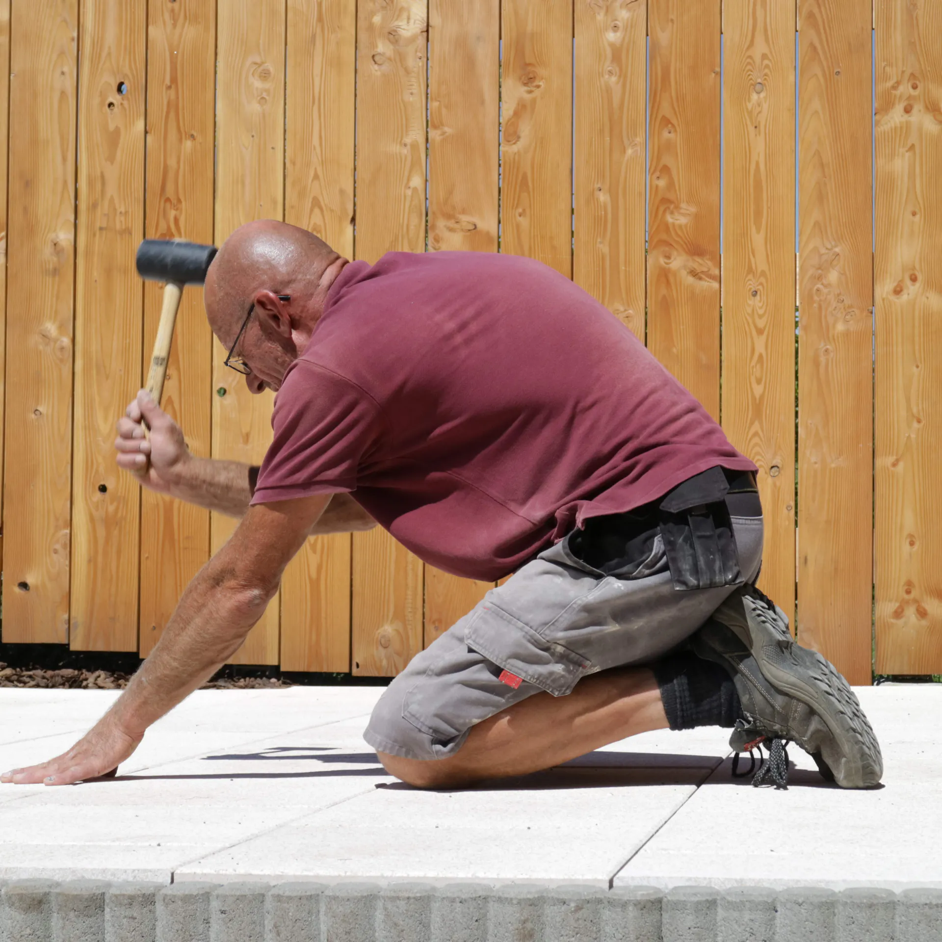 Person schlägt Terrassenplatten mit Gummihammer an.