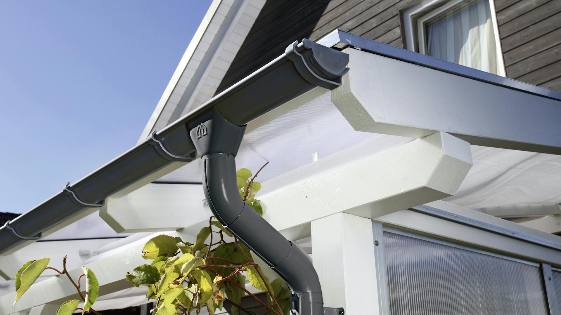 Platten einer Überdachung aus Kunststoff mit Regenrinne.