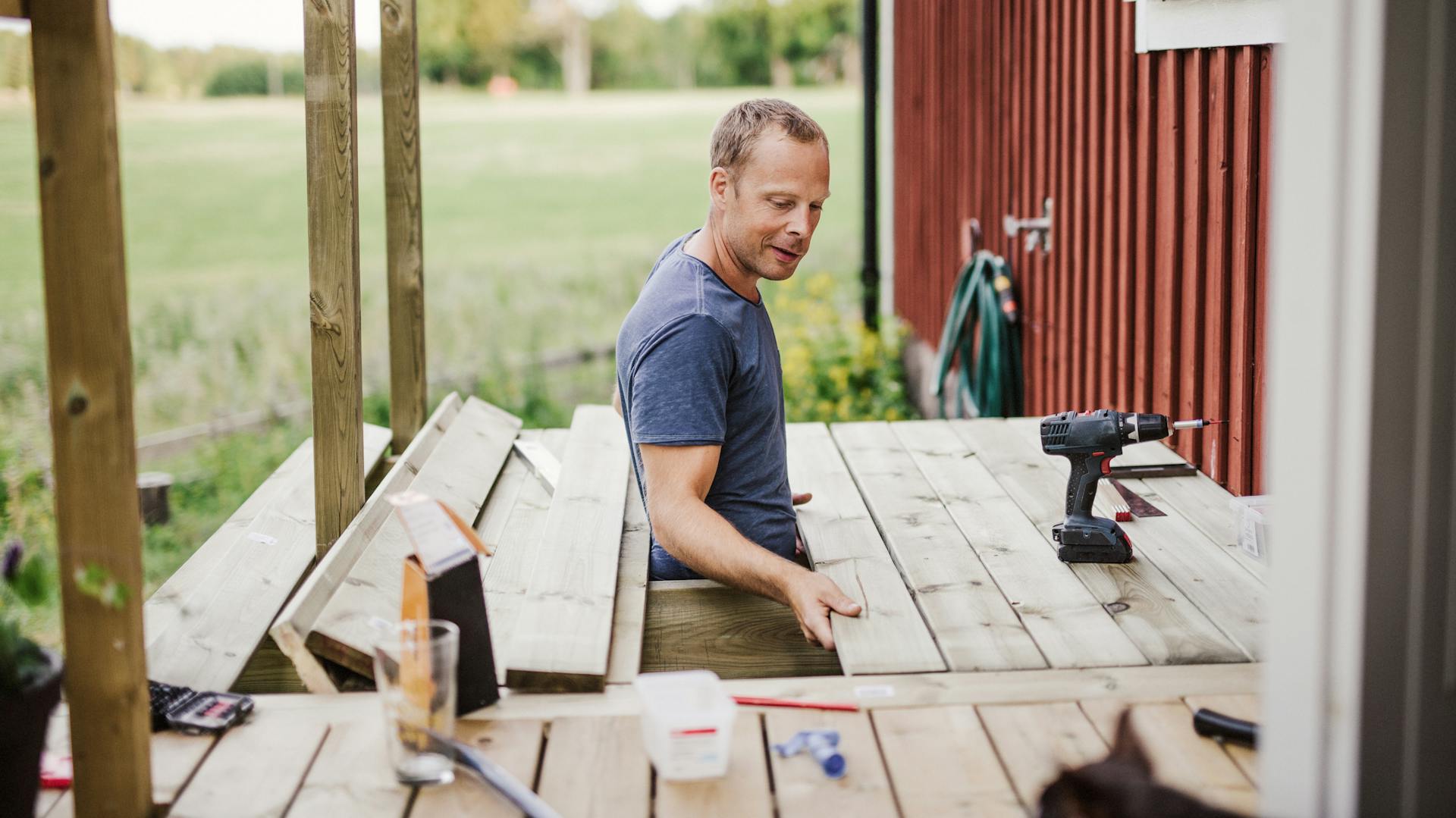 Un uomo posa le assi per una terrazza in legno.