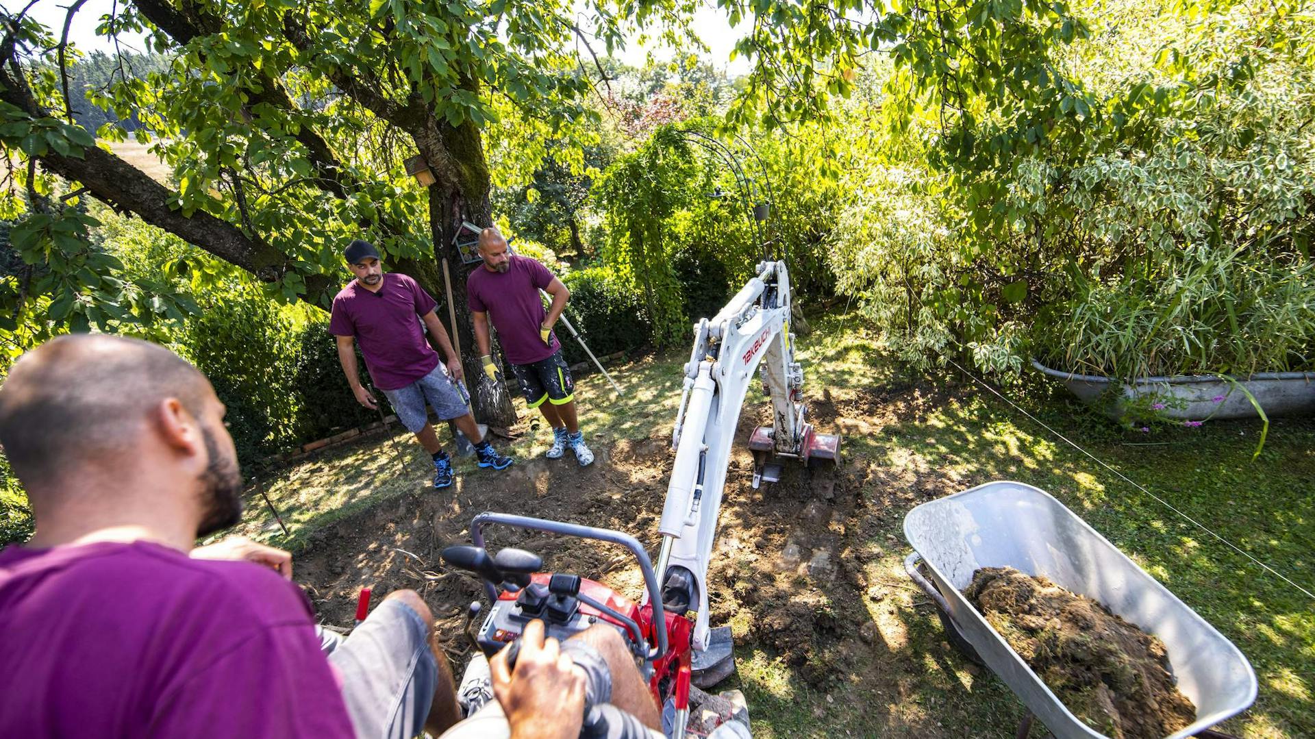 Bauarbeiter heben Erde mit einem Bagger aus