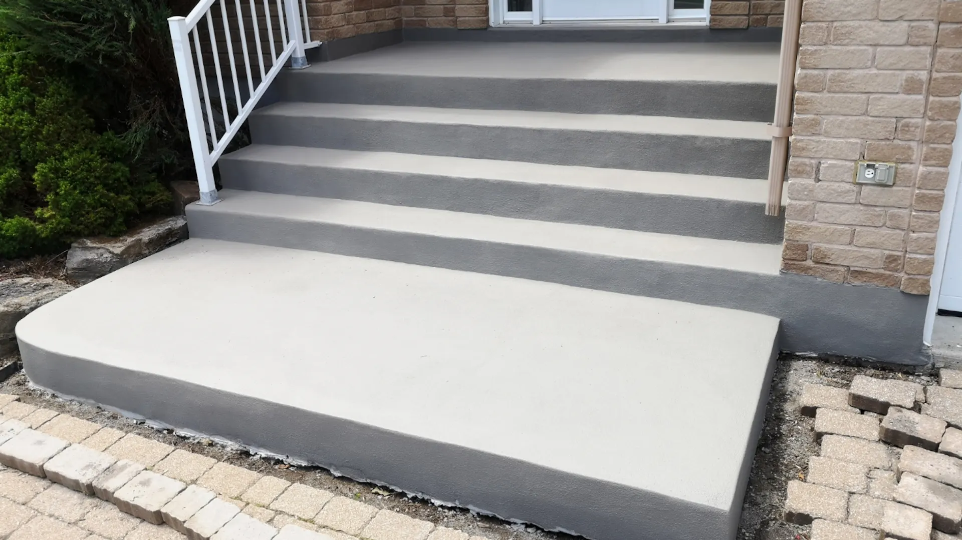 Frisch sanierte Außentreppe aus Beton, davor noch teilweise aufgeschlagener Gehweg.