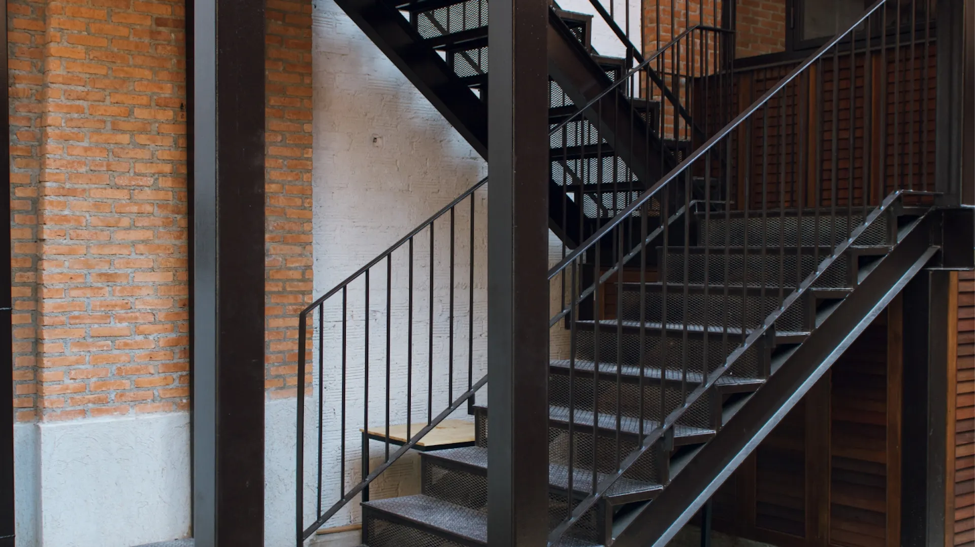 Es ist eine Treppe aus schwarzem, strukturiertem Metall mit Geländer zu sehen.