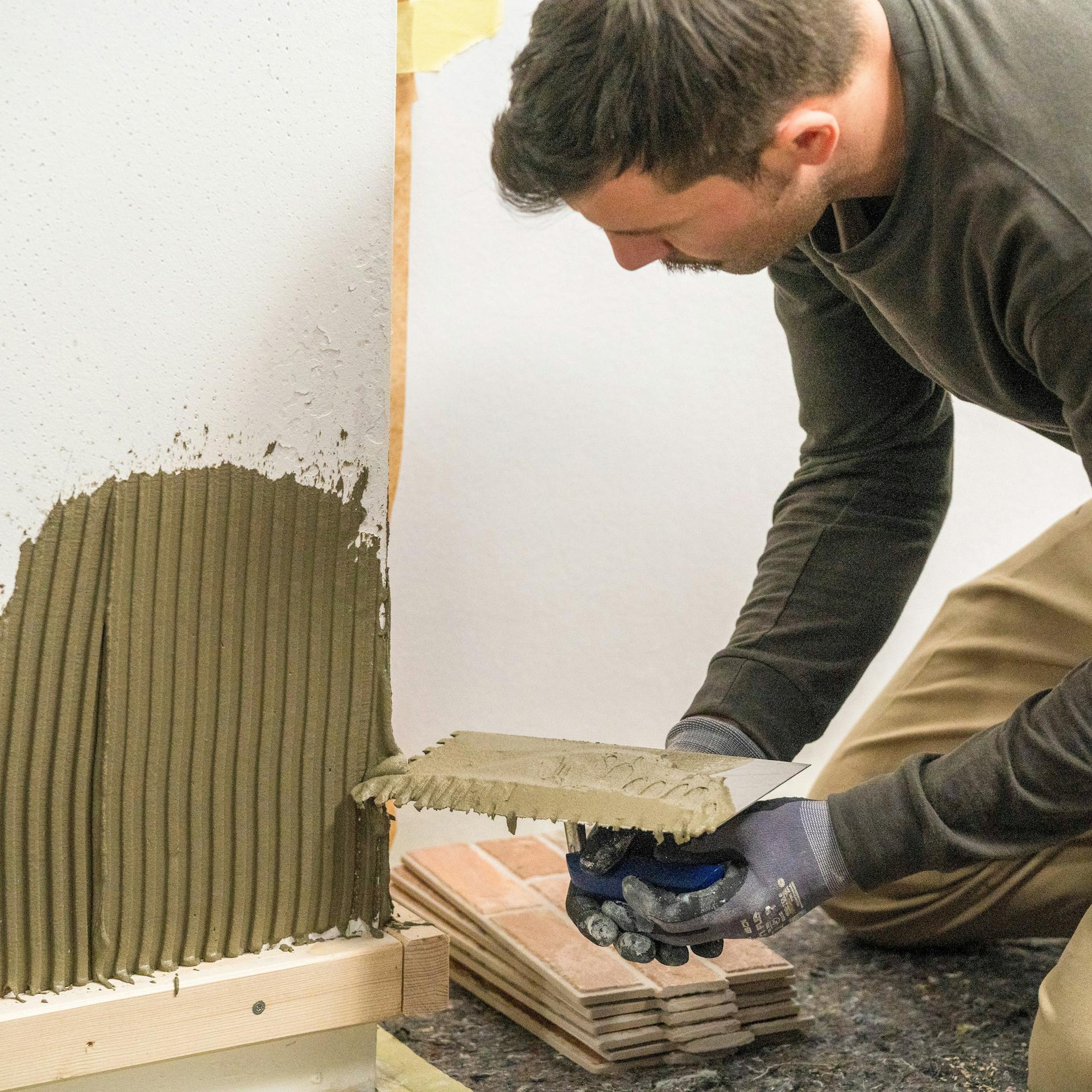 Heimwerker bringt die erste Reihe Verblendsteine an die Wand an.