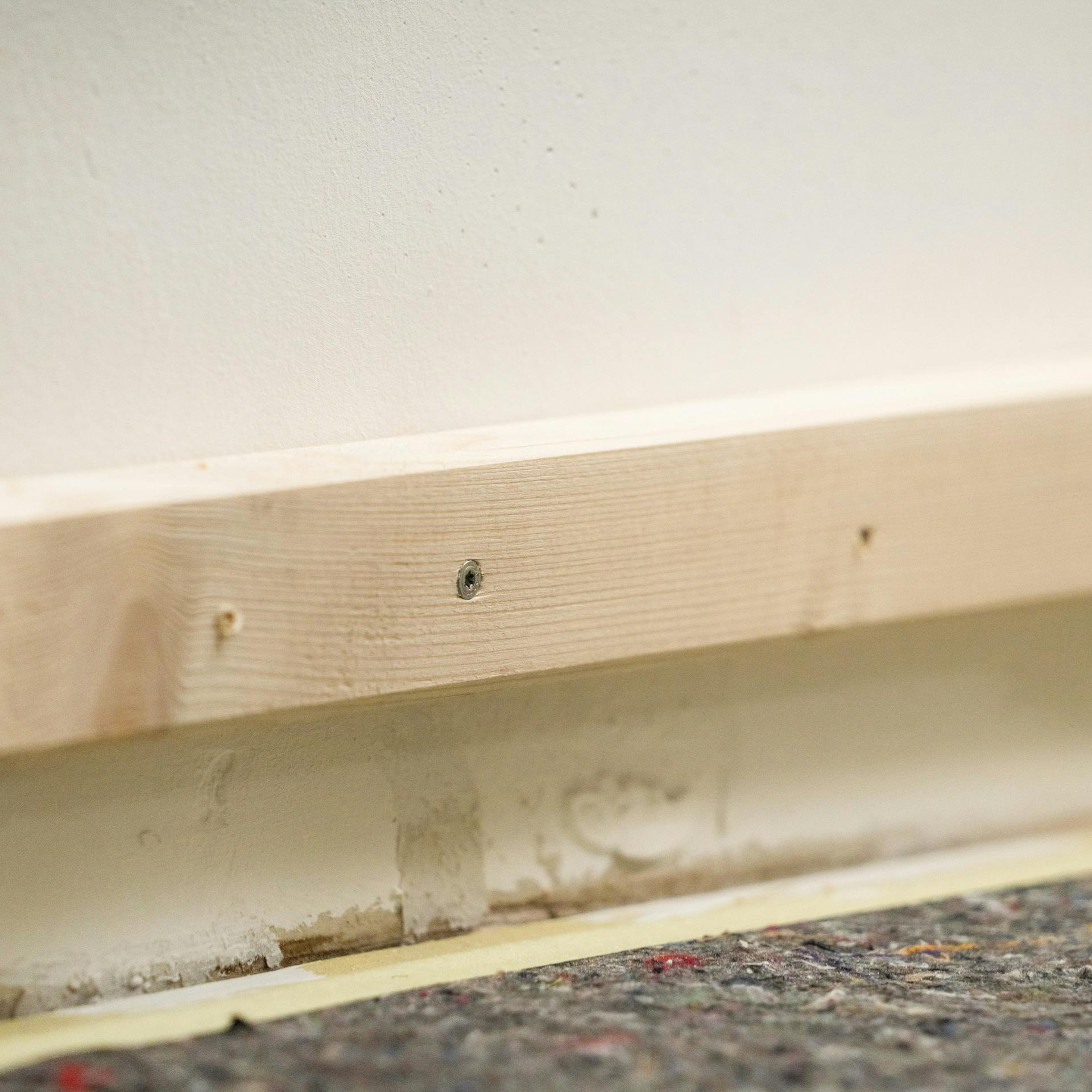 Eine Hilfslatte aus Holz an einer Wand.