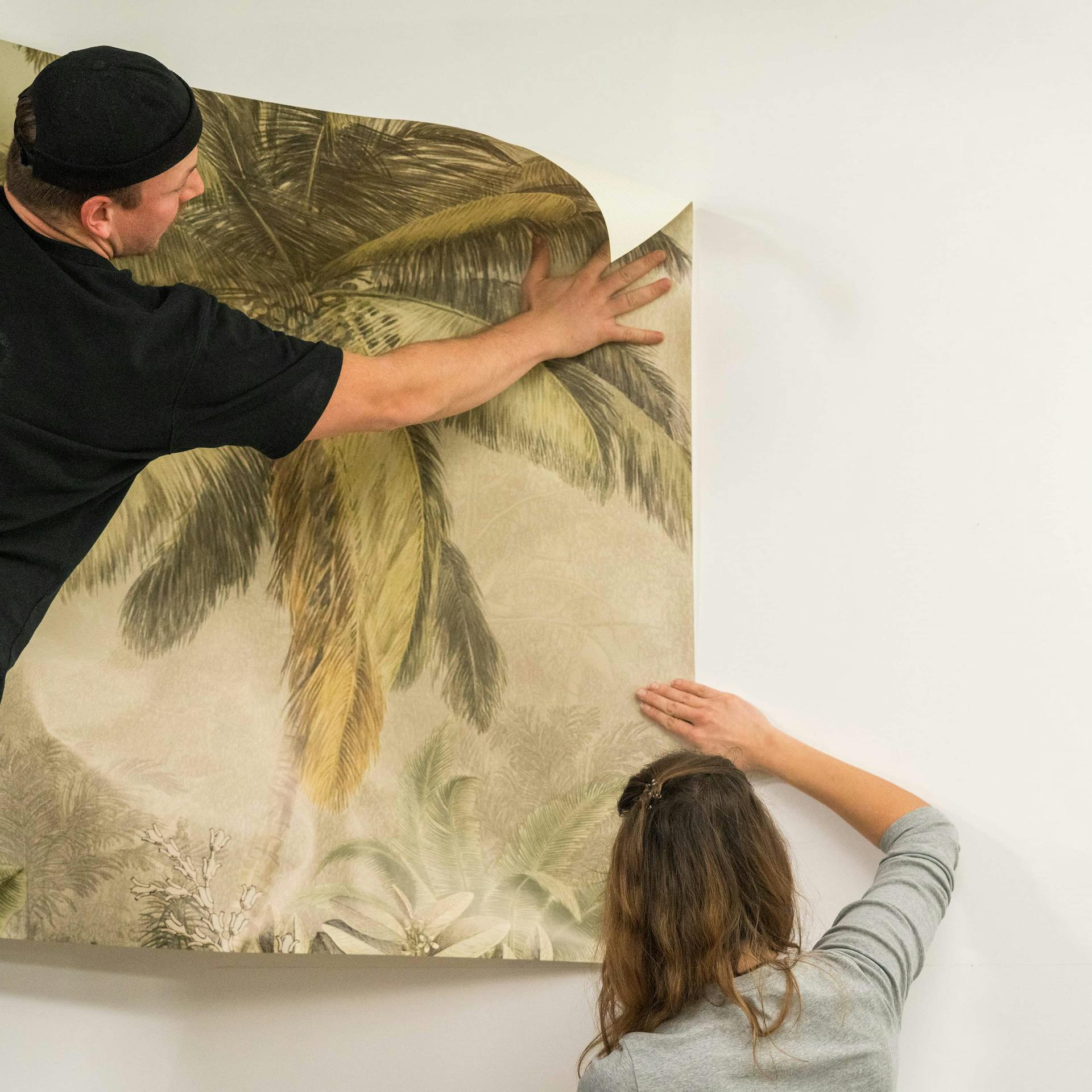 Zwei Personen bringen eine Bahn Fototapete an.