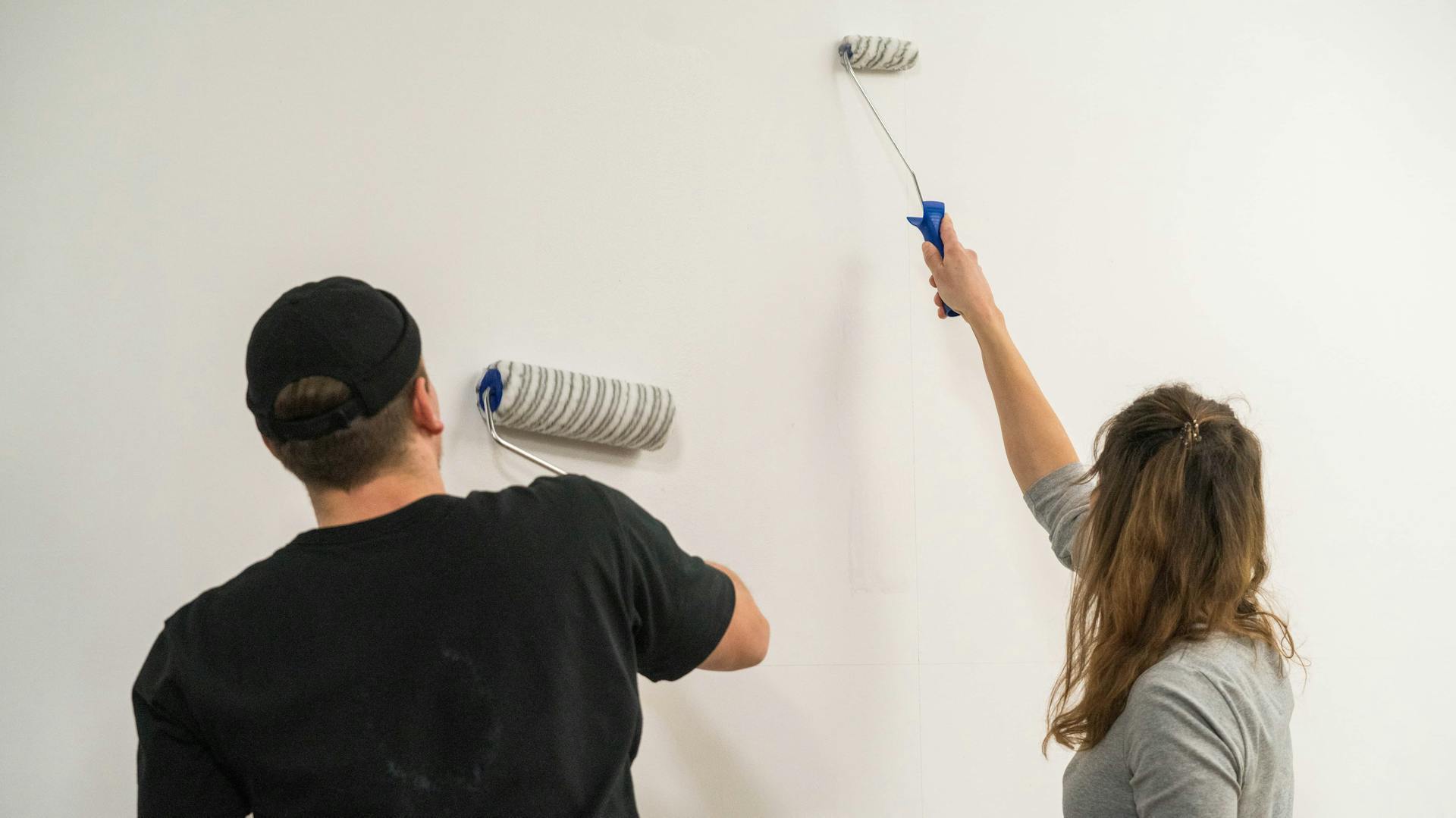Zwei Personen verteilen Kleister auf einer Wand.