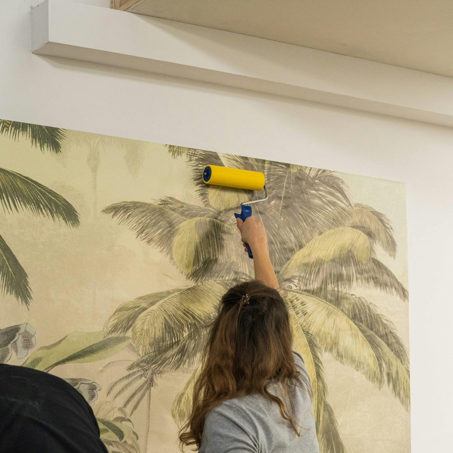 Eine Person entfernt Bläschen aus einer Fototapete mit Tapetenroller.