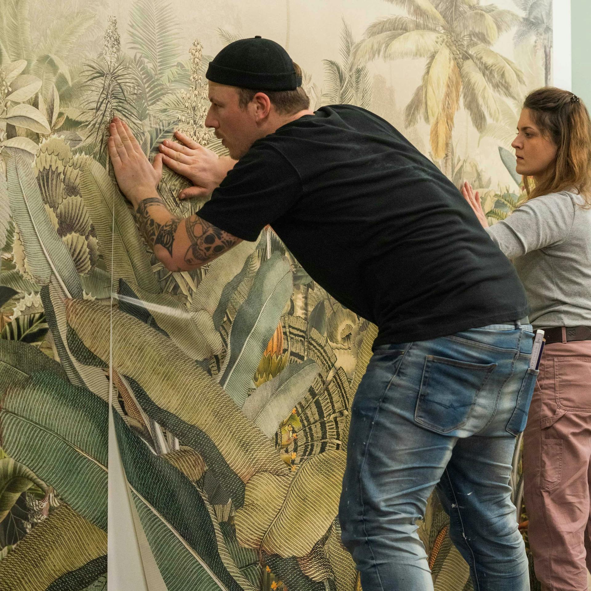 Zwei Personen bringen eine Fototapete Naht auf Naht an.