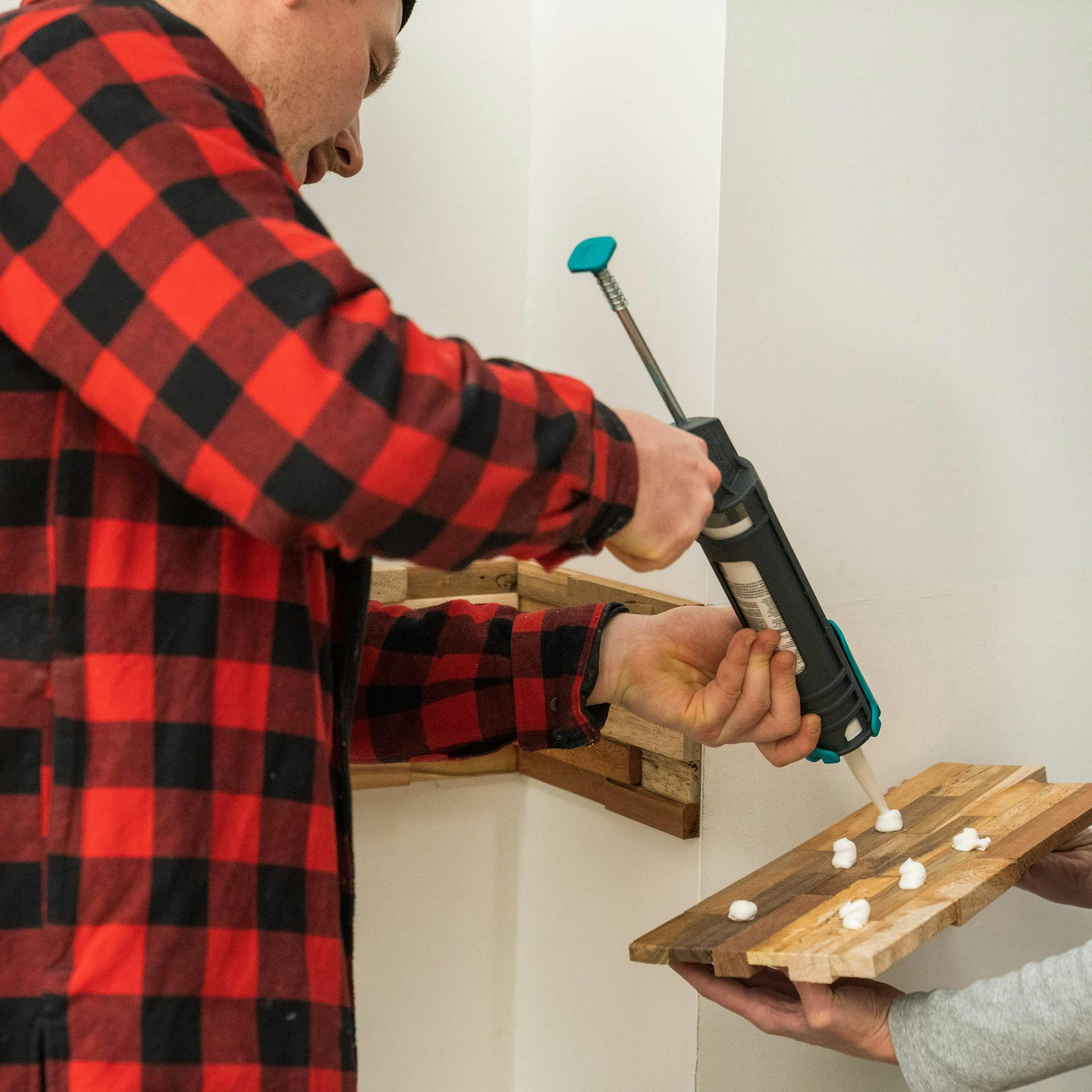 Zwei Personen bringen Holzverblender an einer Ecke an.