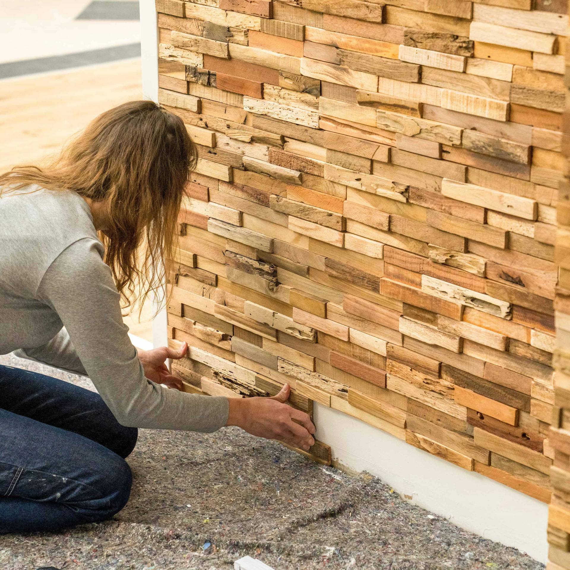 Jemand bringt die untere Reihe einer Holzverblendung an.