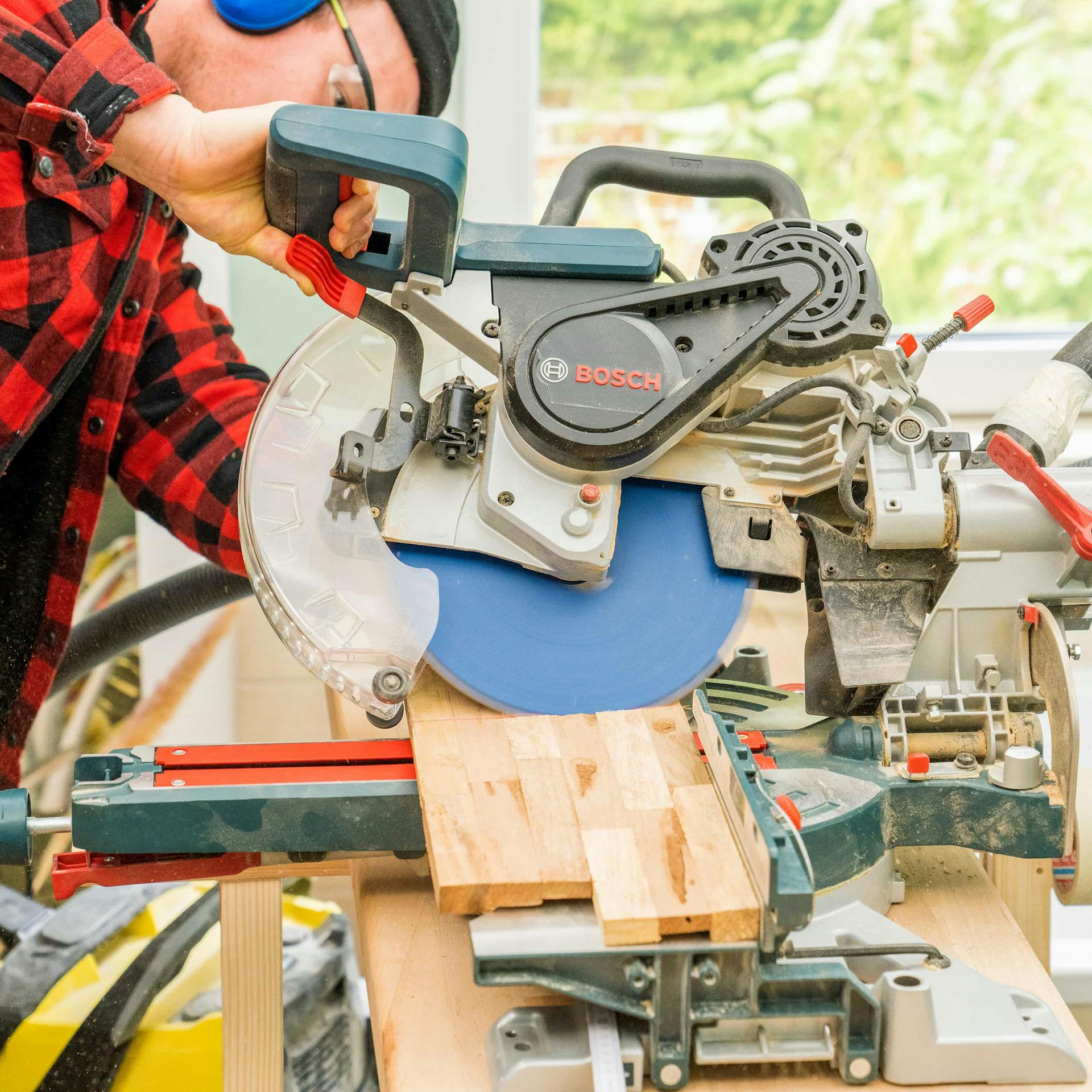 Jemand schneidet einen Holzverblender mit einer Säge zu.