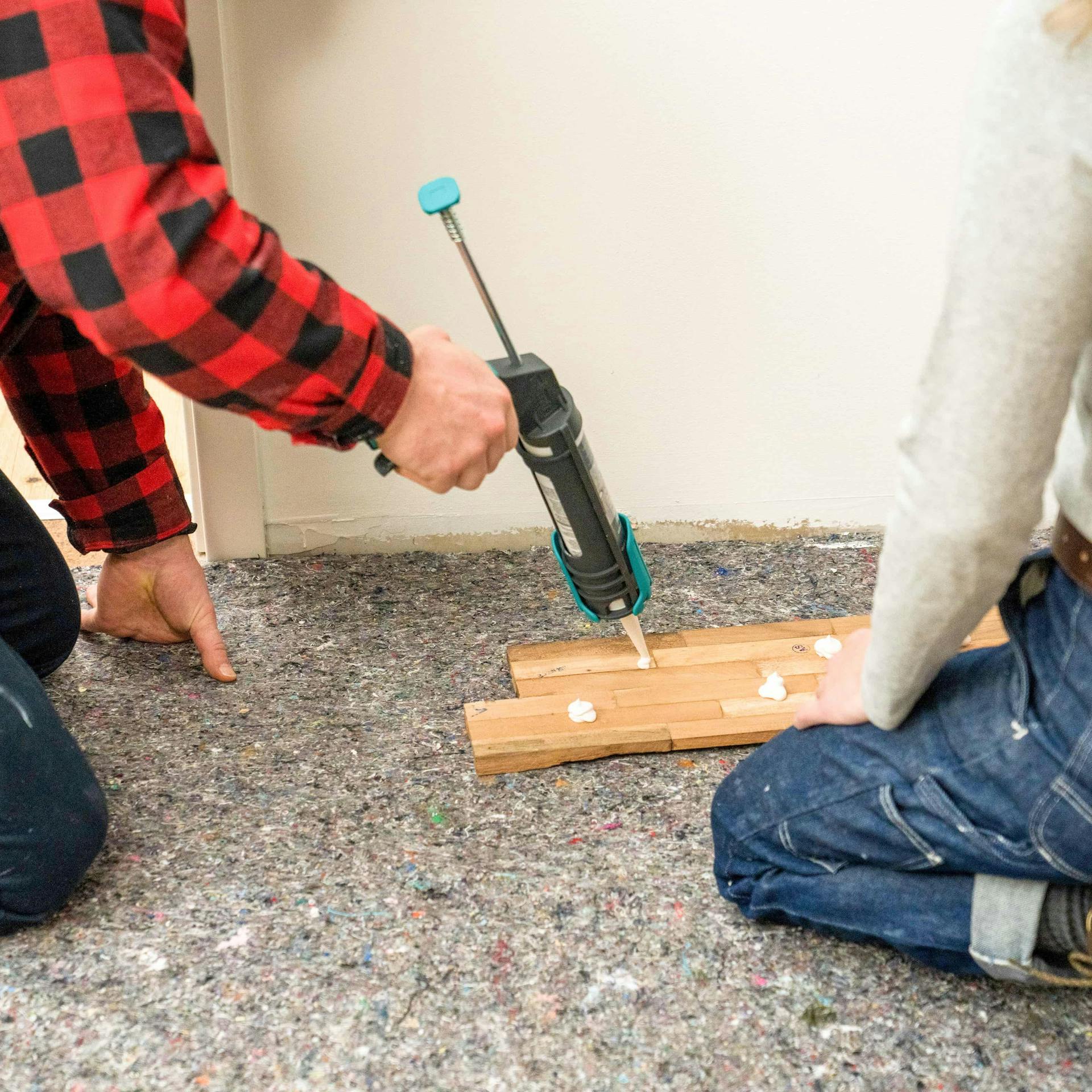 Jemand trägt Montagekleber auf einen Holzverblender auf.