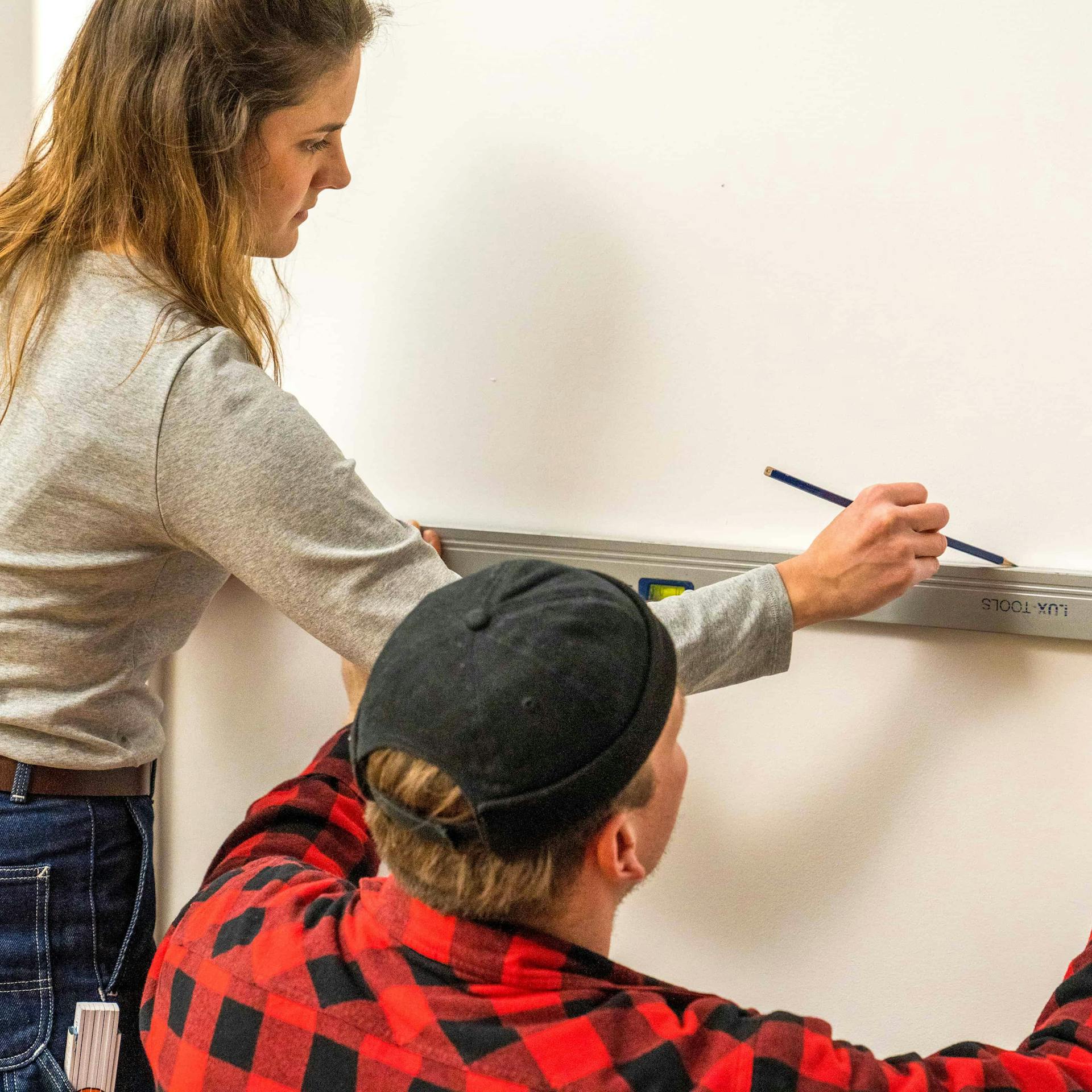 Zwei Personen markieren den Bereich für einen Holzverblender mit Zollstock und Stift.