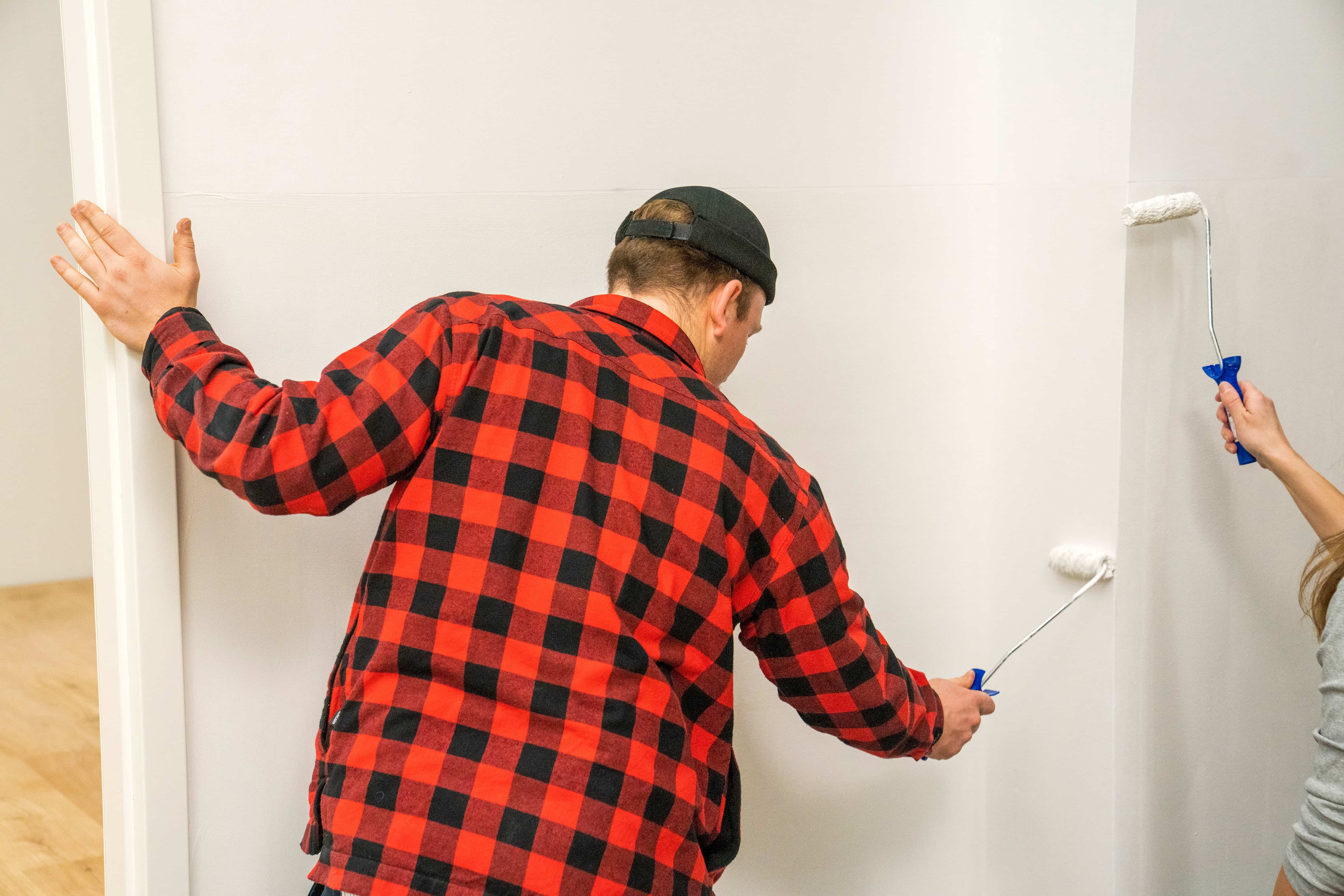 Zwei Personen grundieren eine Wand.