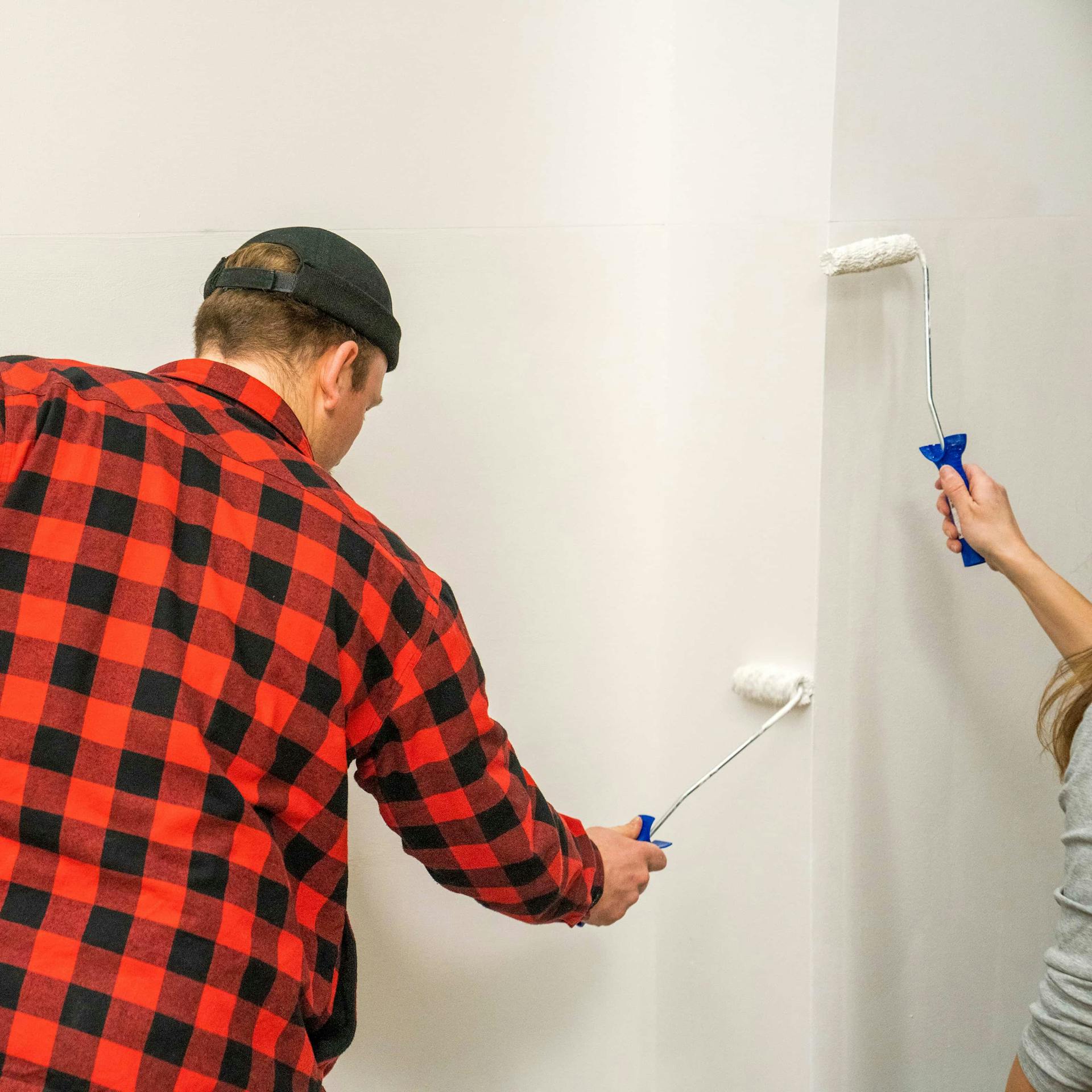 Zwei Personen grundieren eine Wand.