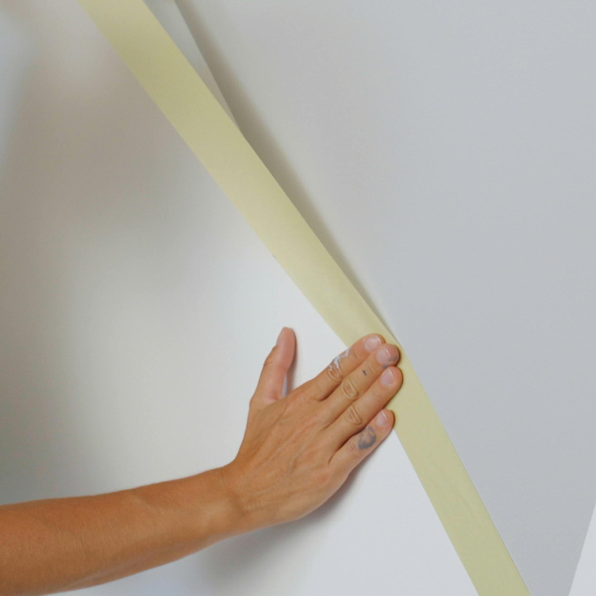 Abkleben einer Wand mit Malerkrepp vor dem Streichen
