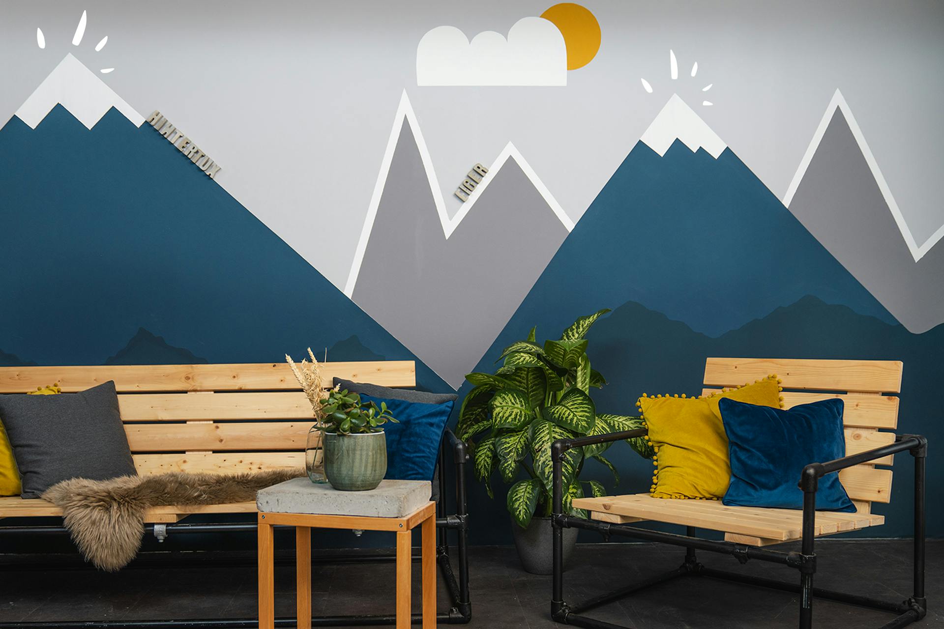 Panca, poltrona e tavolino davanti a un paesaggio montano sulla parete