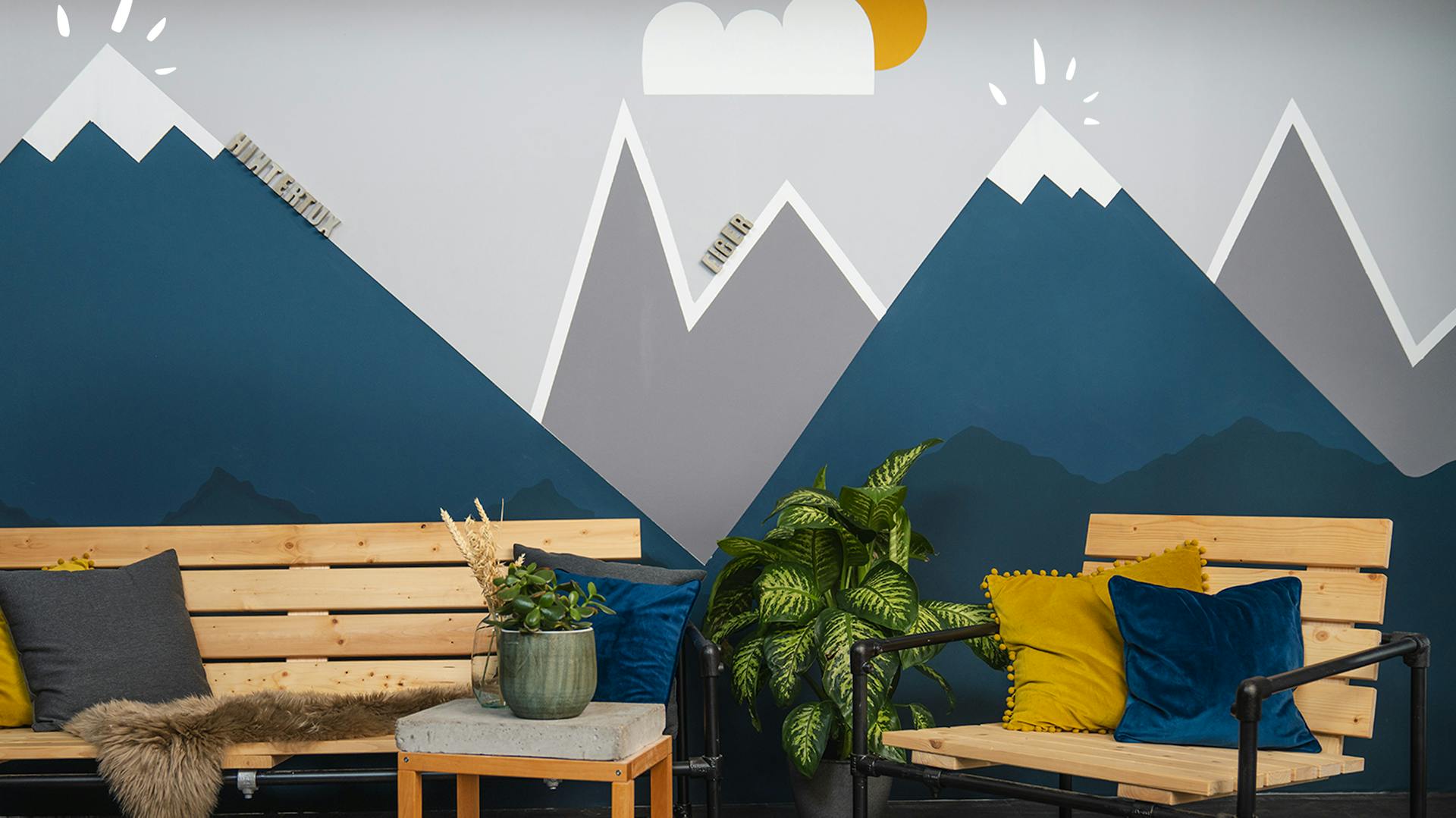 Bank, Sessel und Beistelltisch vor fertiger Berglandschaft an Wand