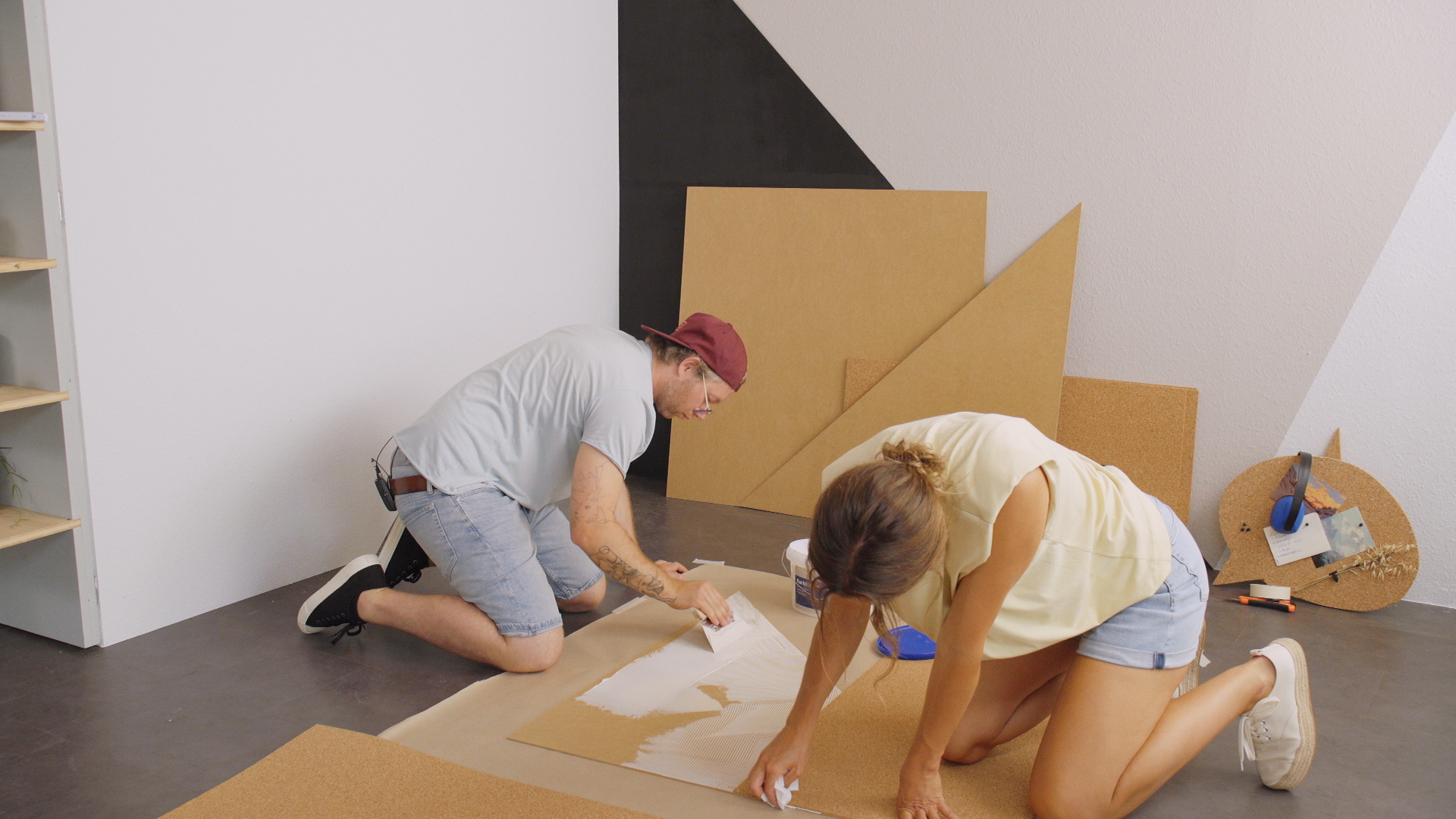 Zwei Heimwerker verkleben Kork mit Trägerplatte für Korkwand