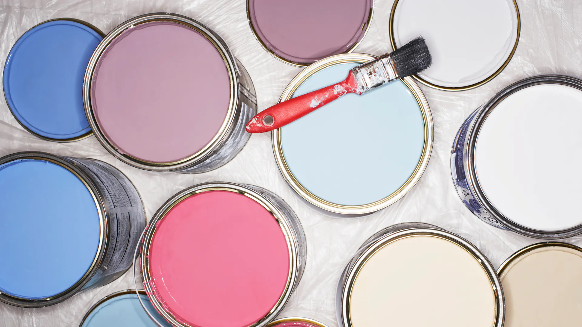 Draufsicht auf Töpfe mit verschiedenfarbigen Latexfarben und Pinsel
