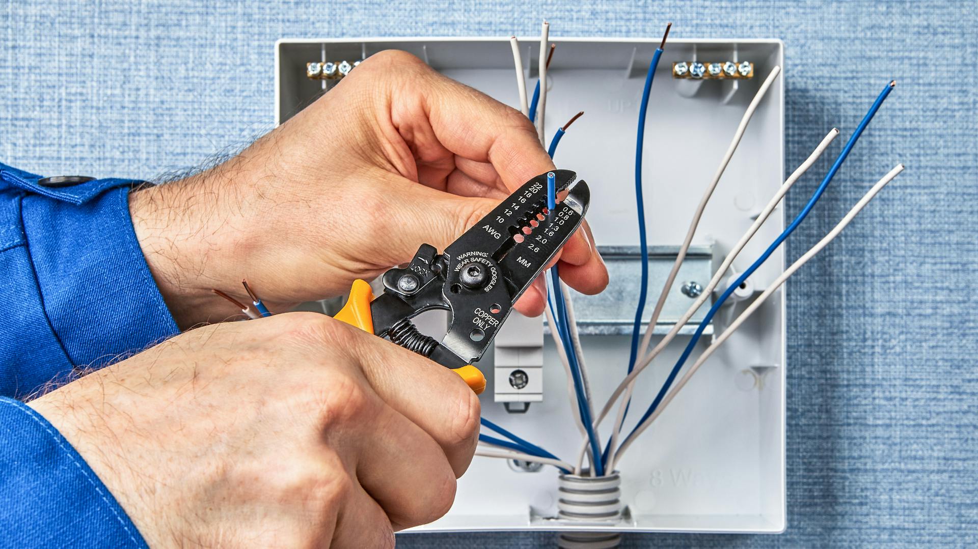 Heimwerker passt aus Leerrohr stehende Kabel mit einer Abisolierzange an.