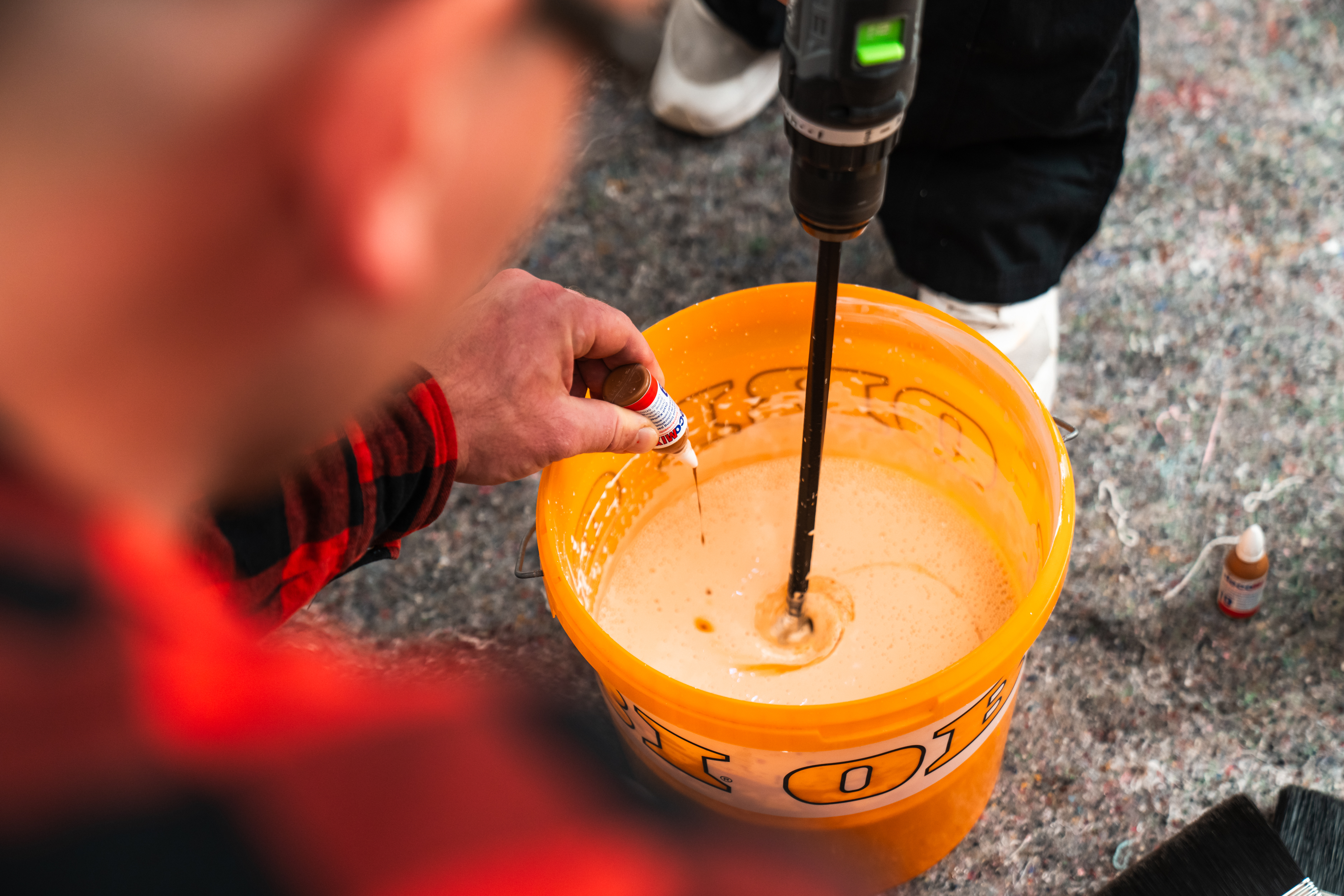 Osoba dáva koncentrát farby do vedra s vodou