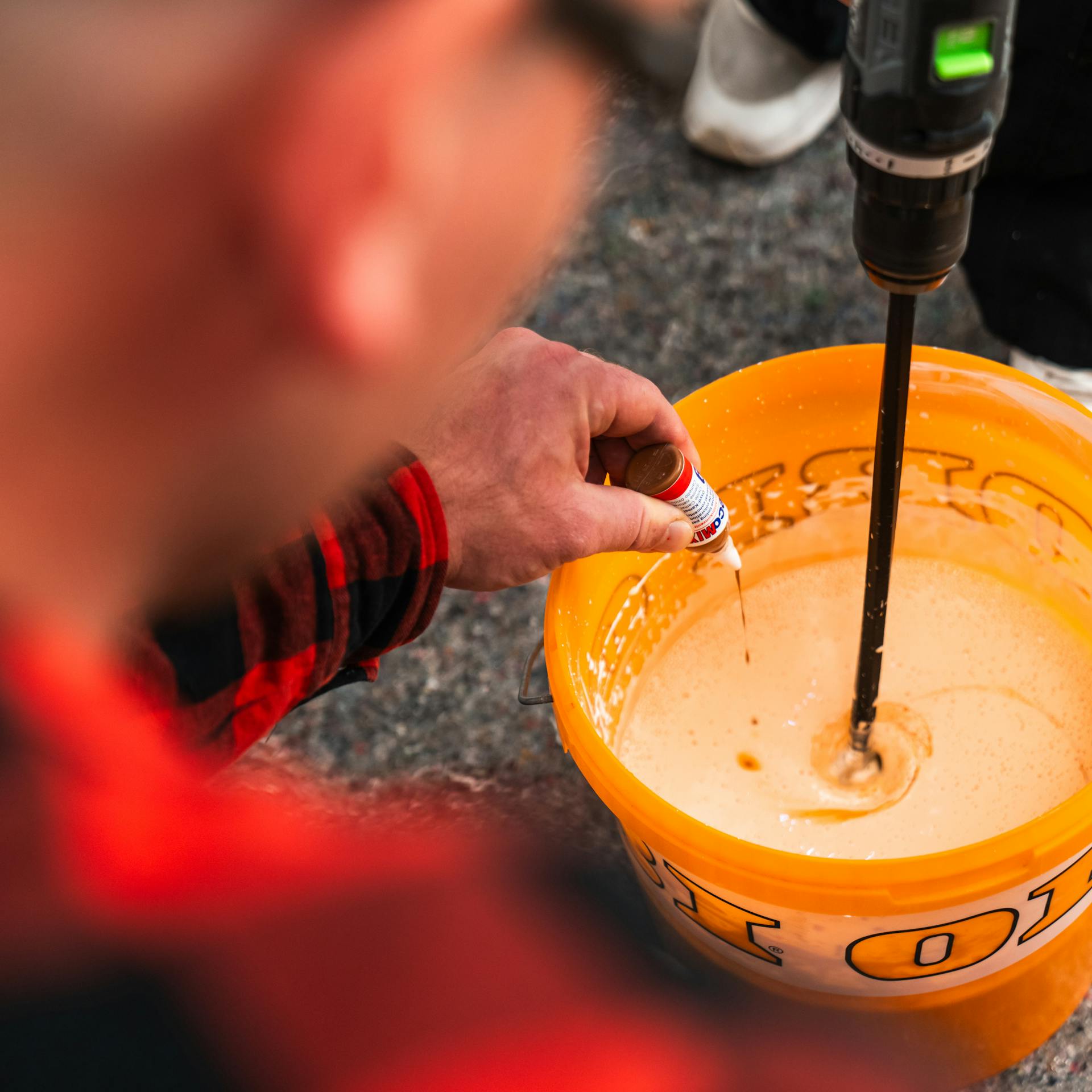 Osoba dáva koncentrát farby do vedra s vodou