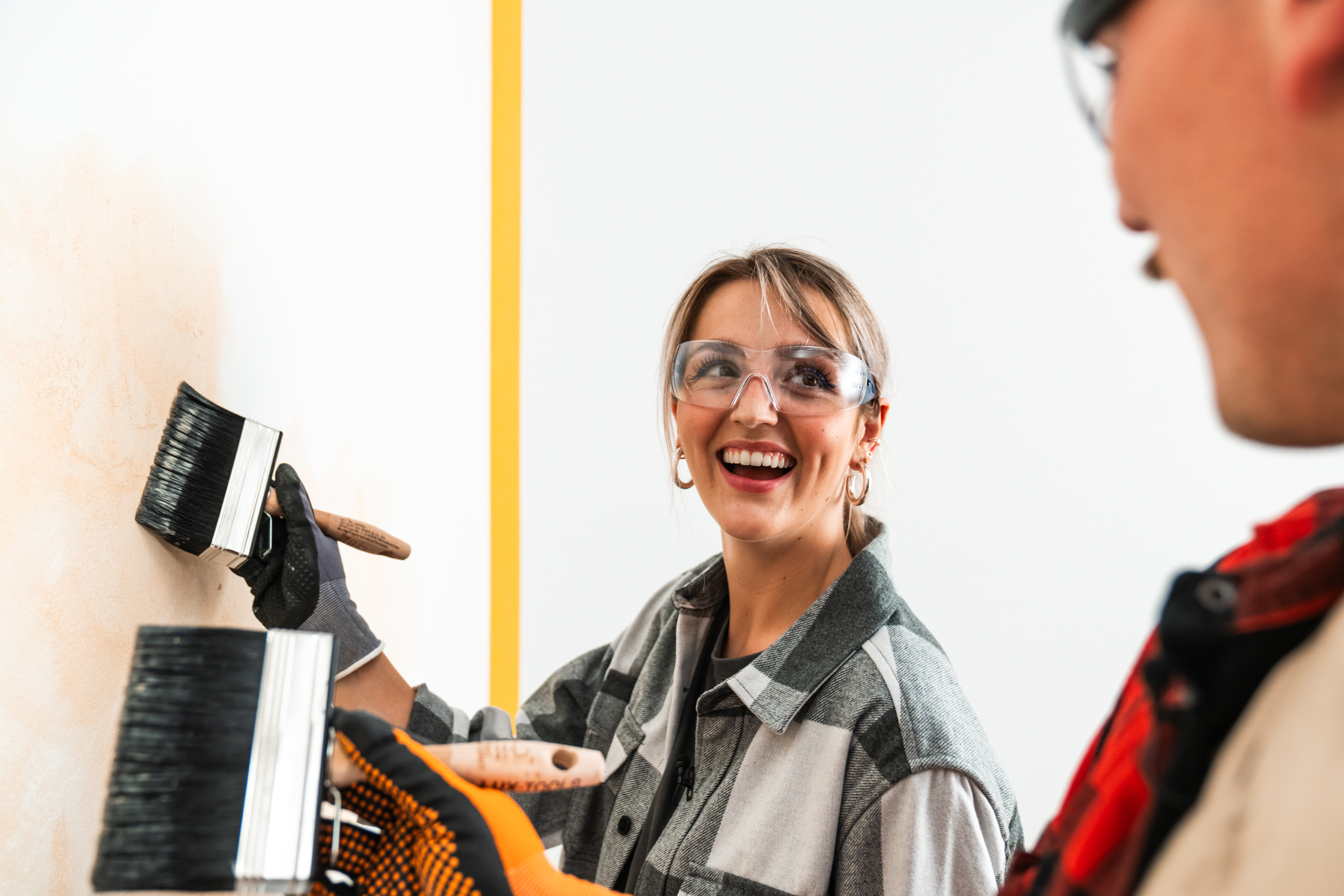 Maliar a maliarka maľujú stenu plochým štetcom