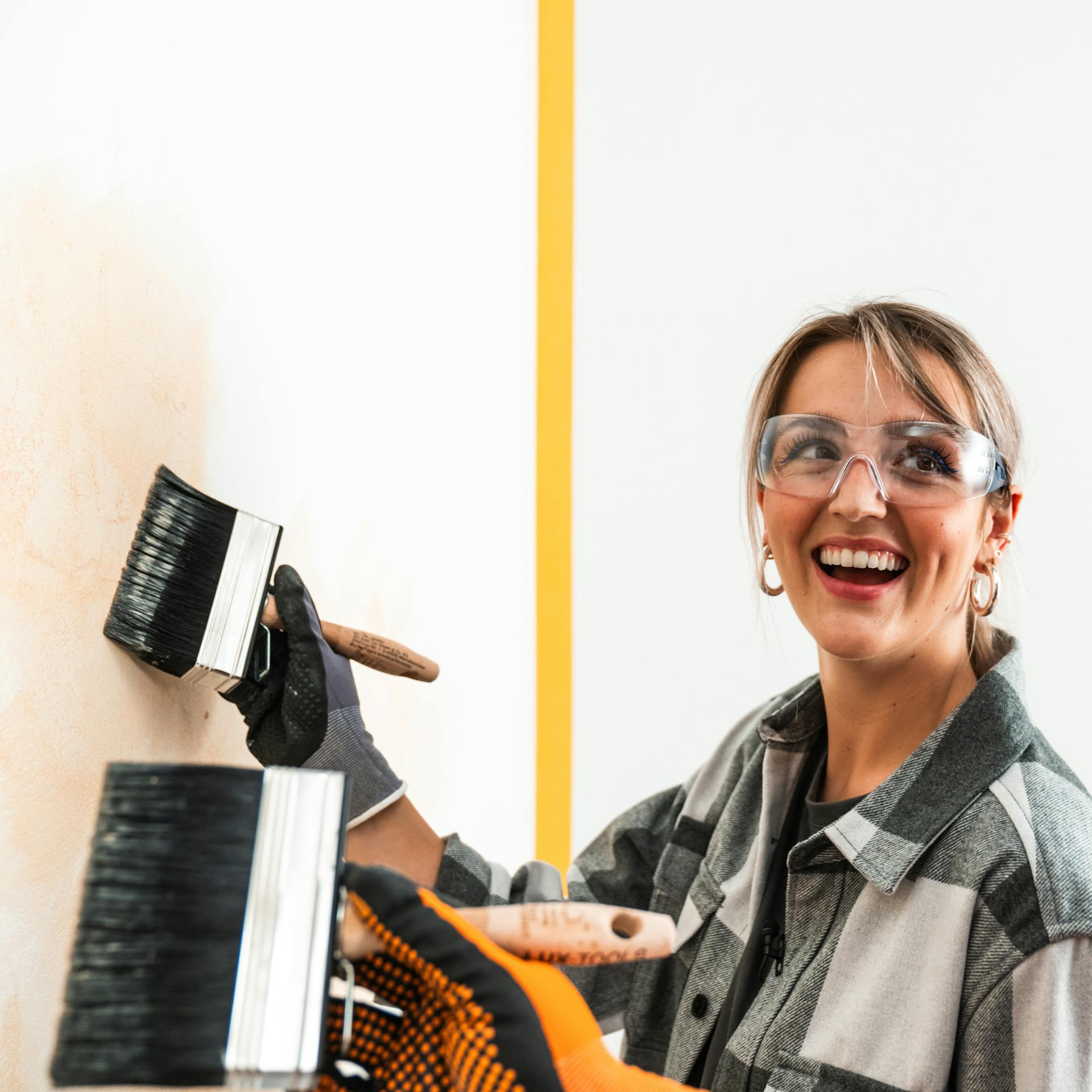 Maliar a maliarka maľujú stenu plochým štetcom