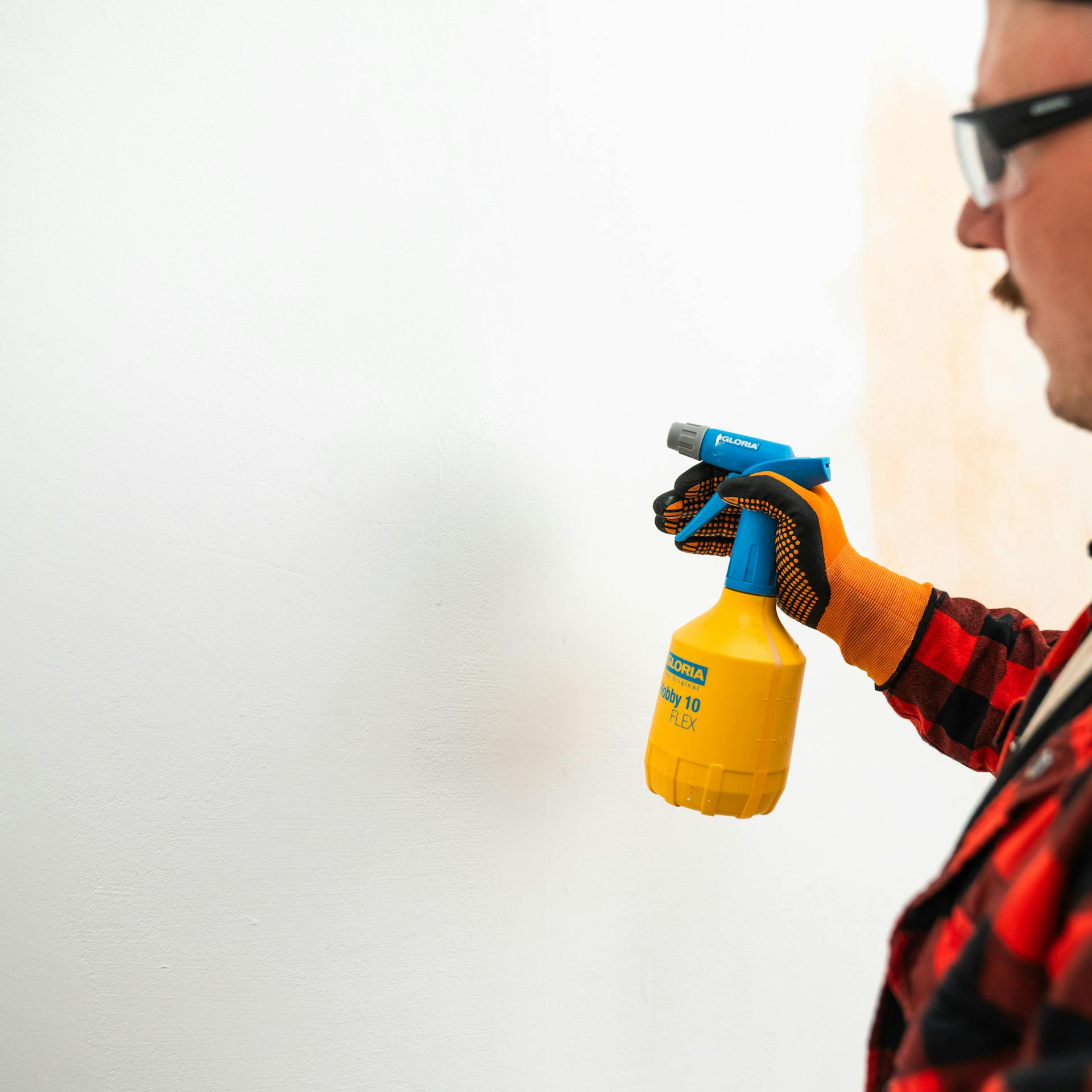 Maliar rozprašuje vodu na stenu pomocou rozprašovača