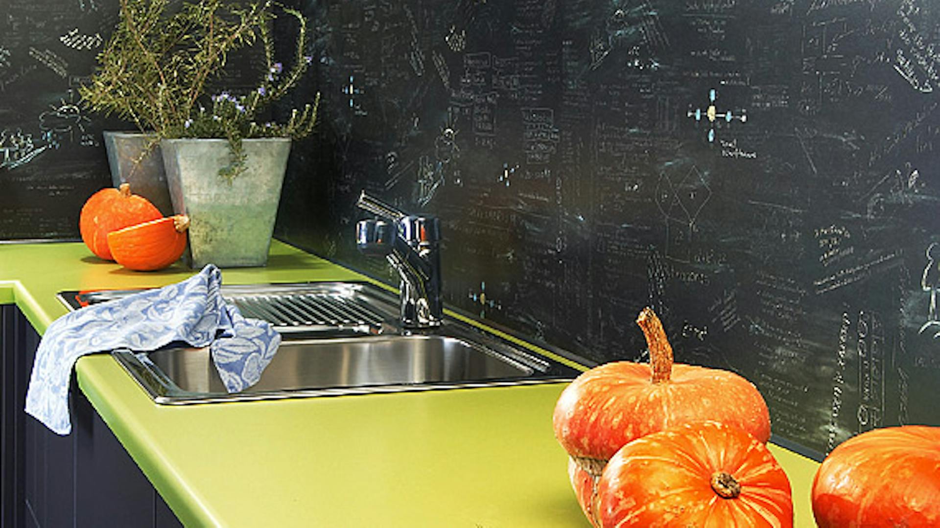 Smalto effetto lavagna sulla parete della cucina dietro il lavello e il piano di lavoro.