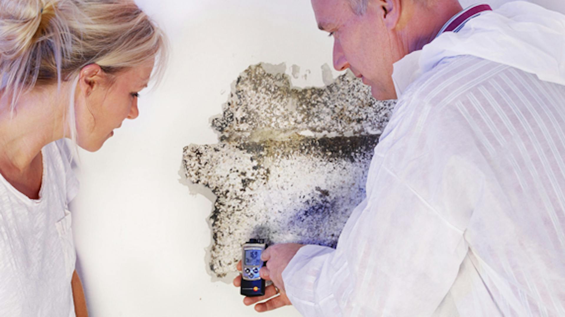 Un uomo e una donna misurano l’umidità nella parete.