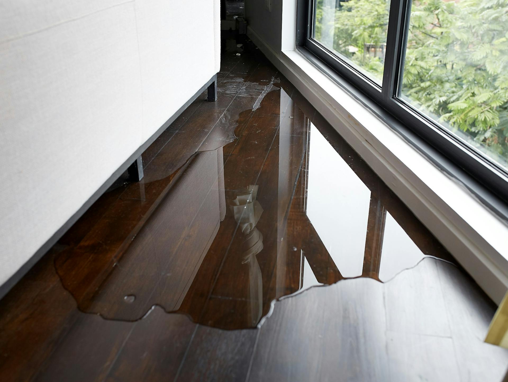 Wasserschaden am Fenster hinter einem Möbelstück.