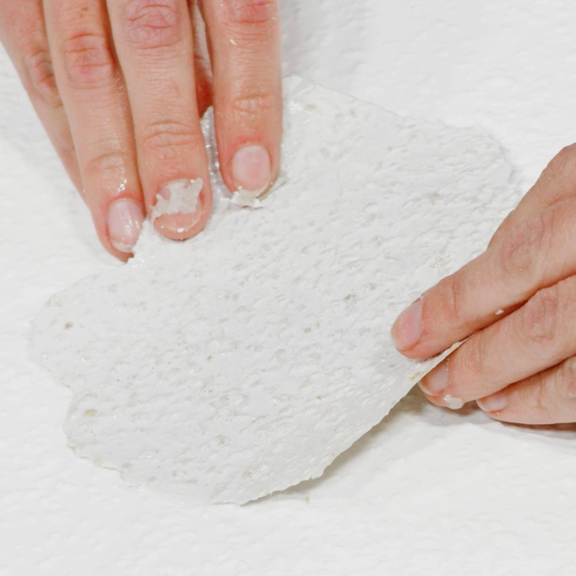 Pracovníci ukazujú, ako opraviť tapetu prilepením kúsku tapety na väčšiu dieru.