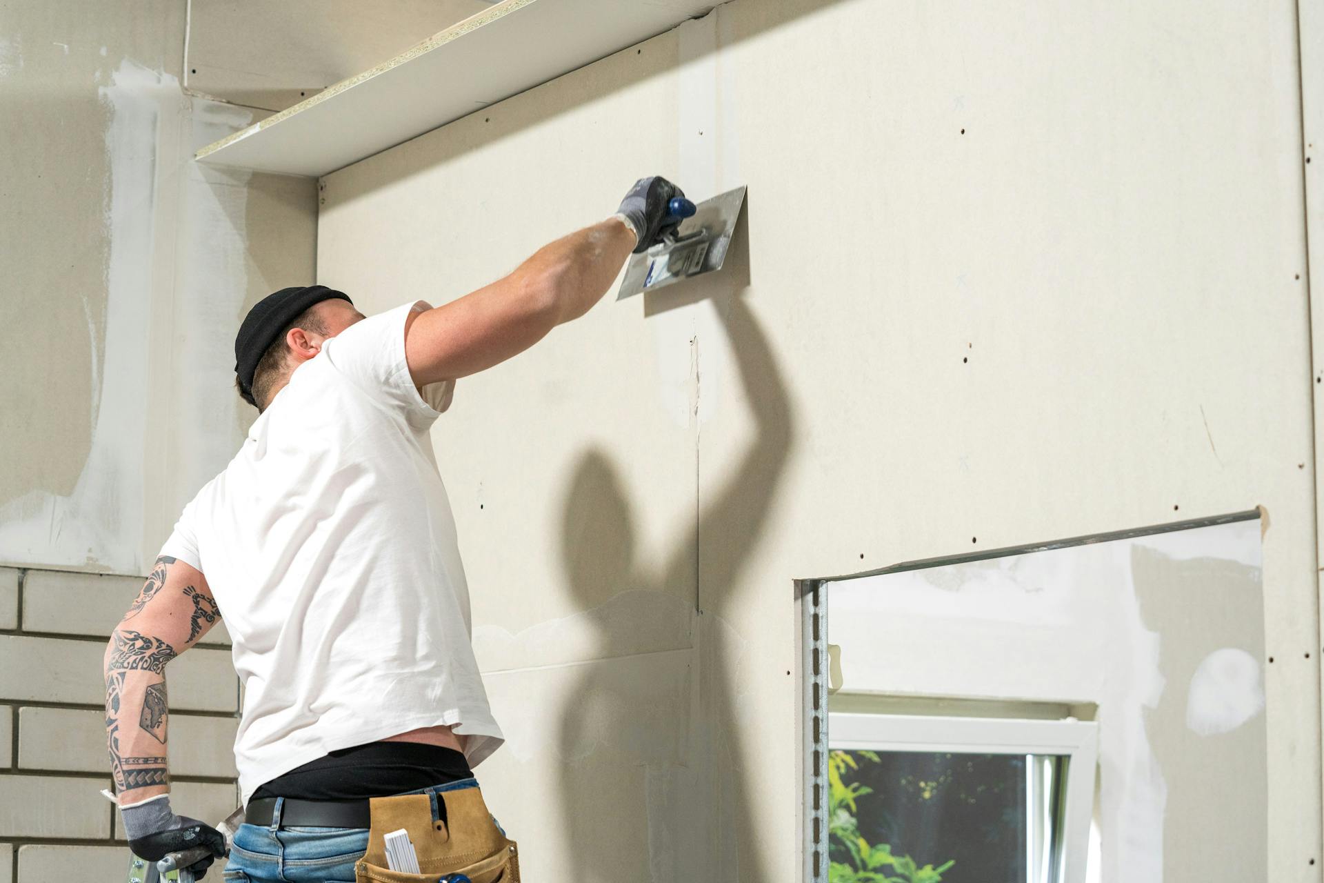 Handwerker verspachtelt die Trockenbauwand mit einem Spachtel.